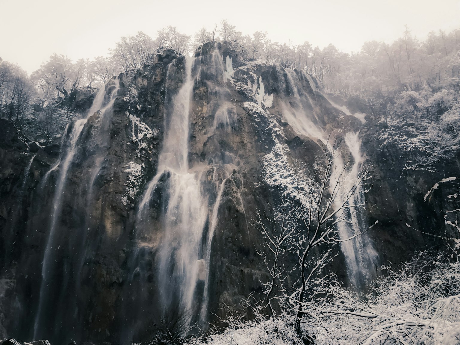 Hermoso paisaje de una cascada que fluye sobre rocas cubiertas de nieve