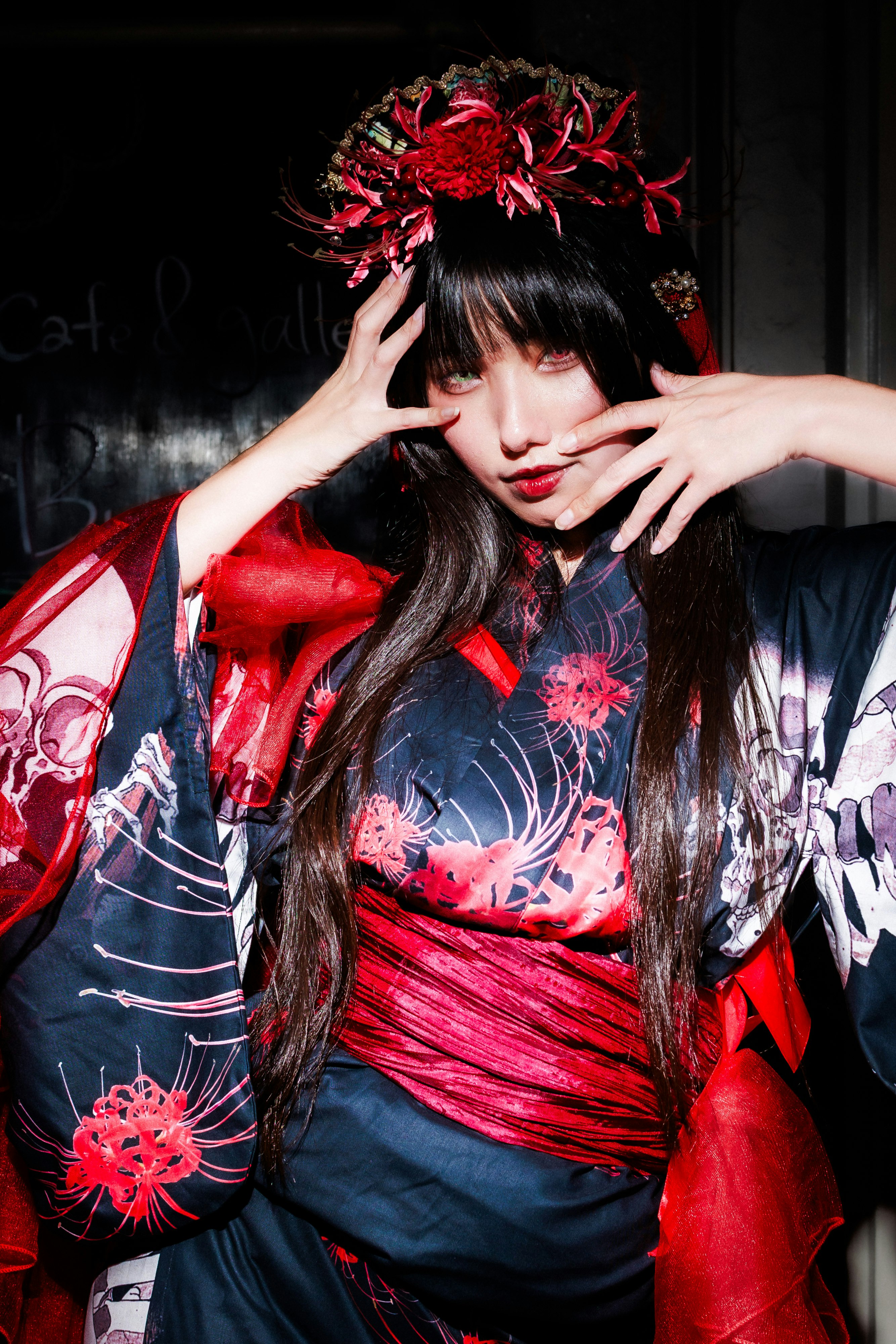 woman in a red floral hair accessory and kimono adjusting her hair in a portrait