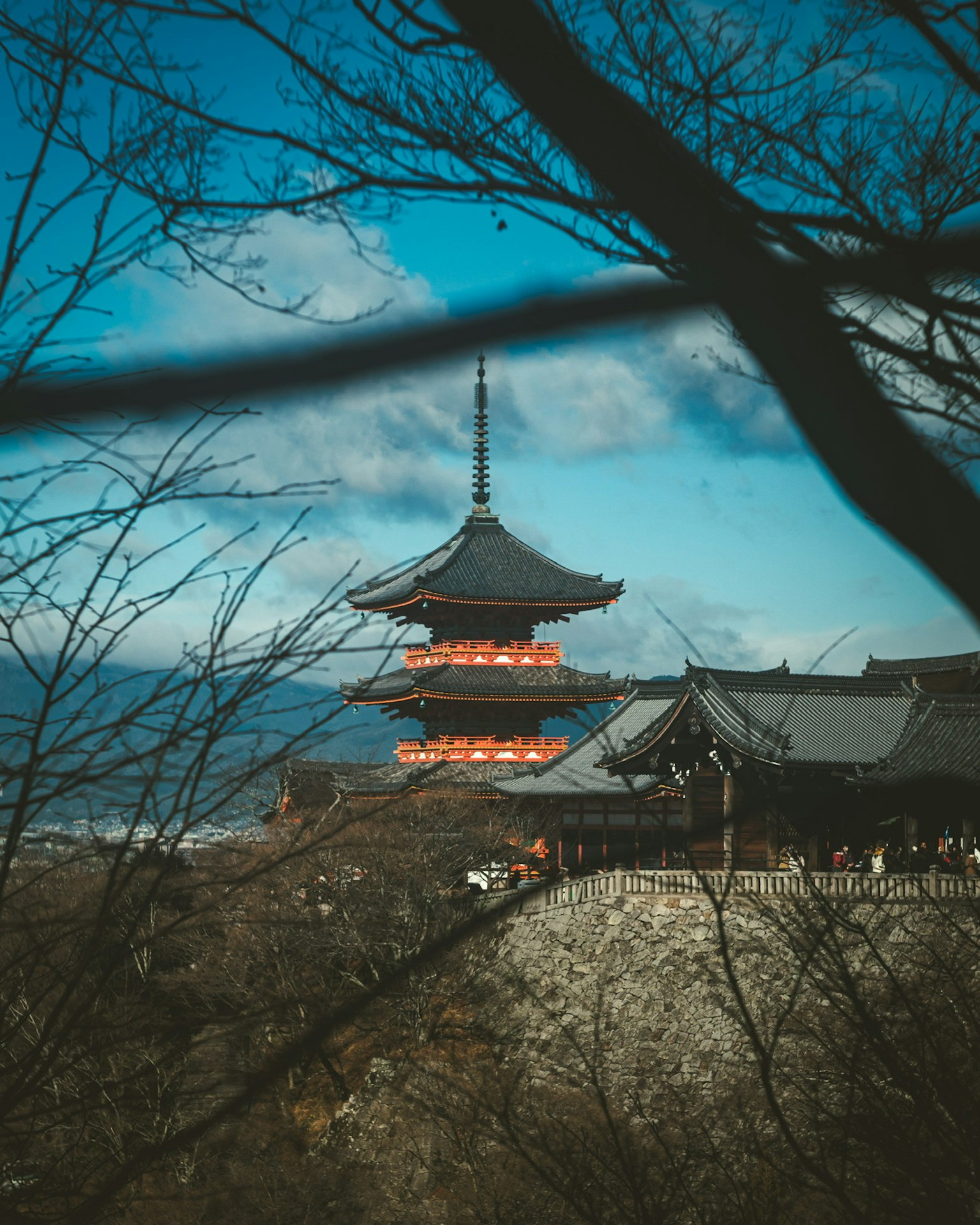 Der Turm des Kiyomizu-dera-Tempels unter einem blauen Himmel mit alten Gebäuden sichtbar