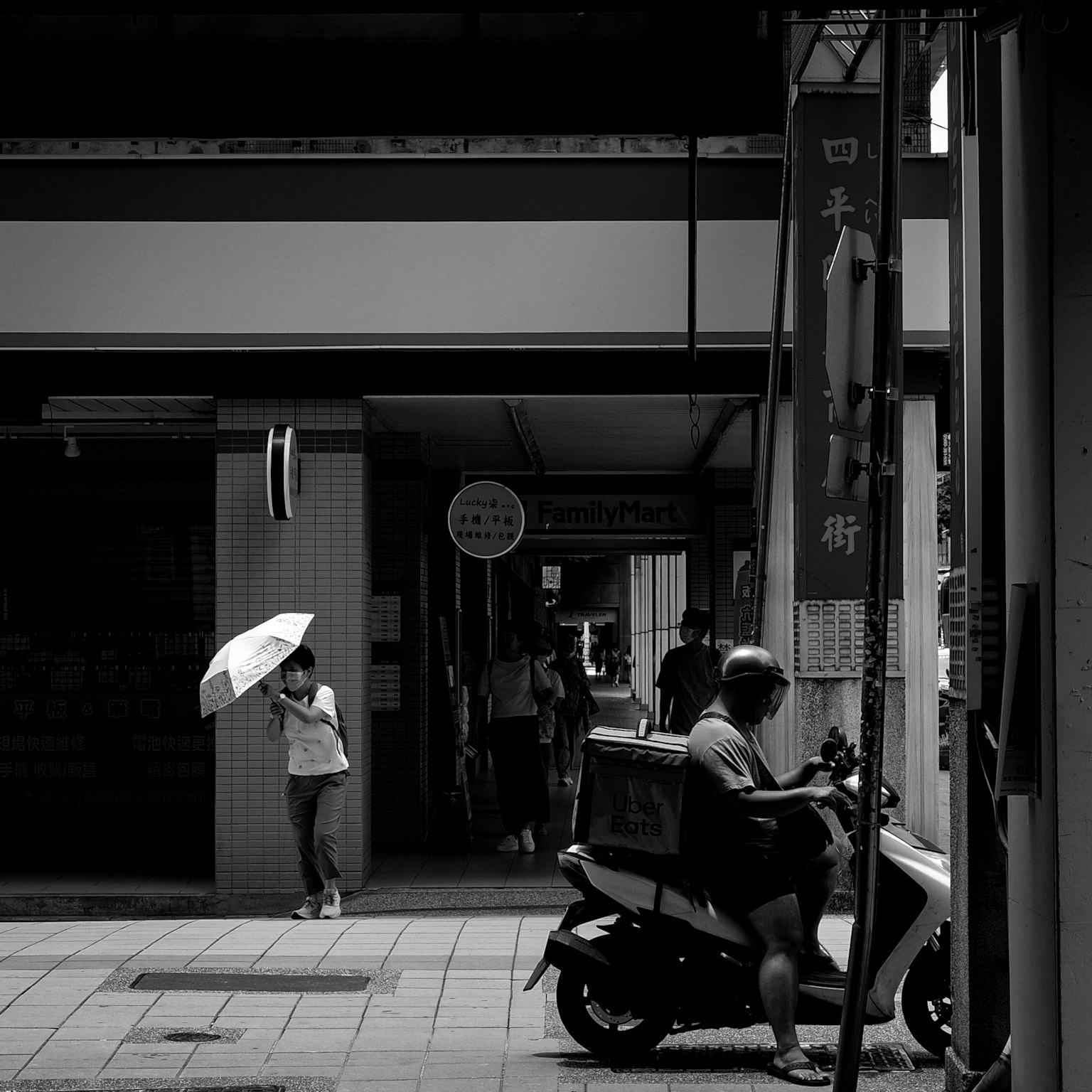 Una escena callejera en blanco y negro con una mujer con un paraguas y un hombre en una motocicleta