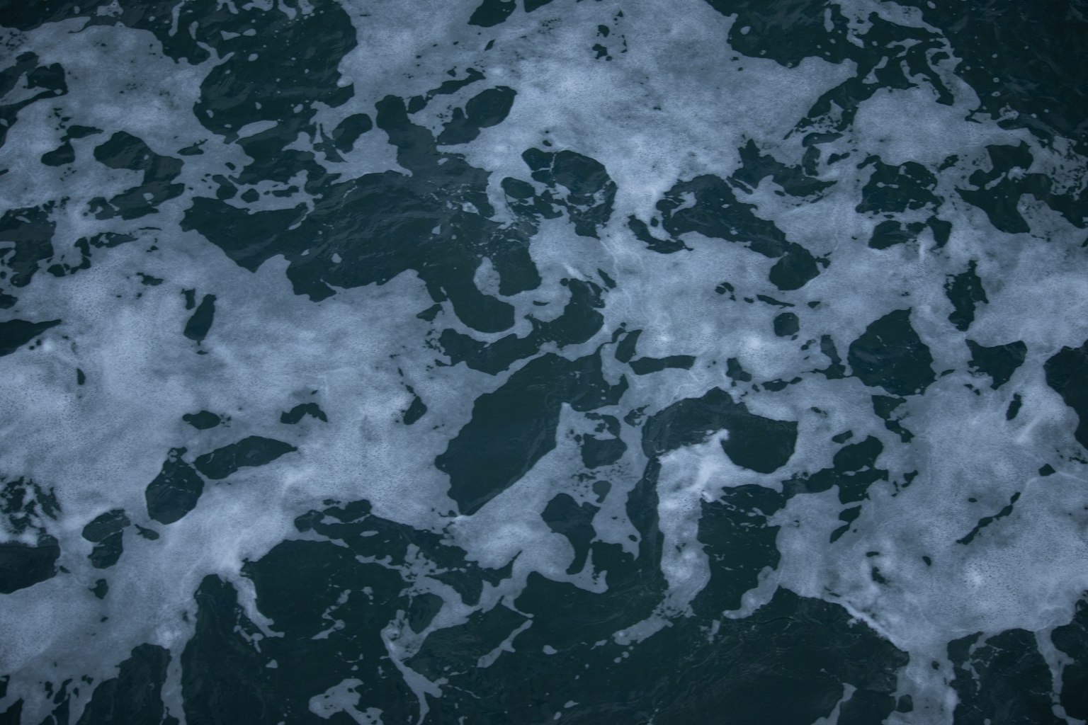 Motifs de mousse et d'eau sur une surface océanique sombre