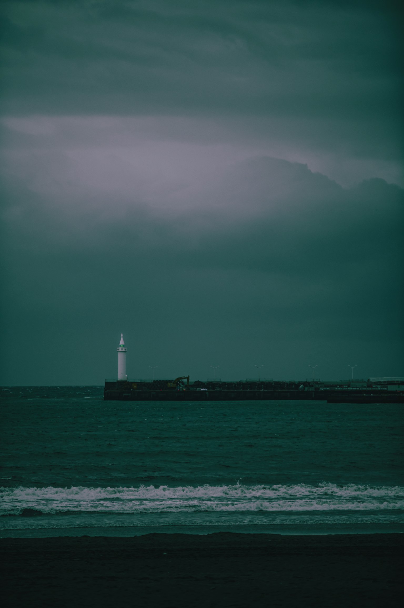 Paesaggio marino d'atmosfera con un faro e nuvole scure