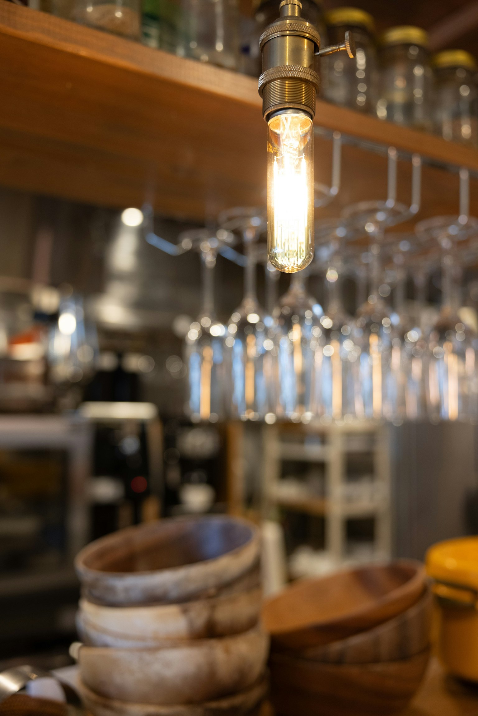 Intérieur d'un café avec des bols en bois et des verres suspendus avec une ampoule lumineuse