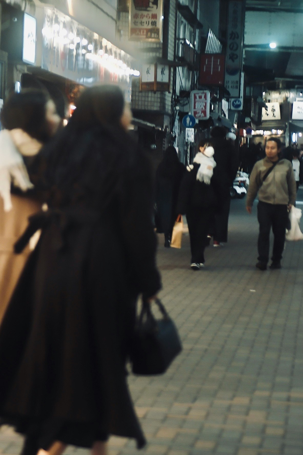 夜の街を歩く人々の姿と暗い服装の女性たち