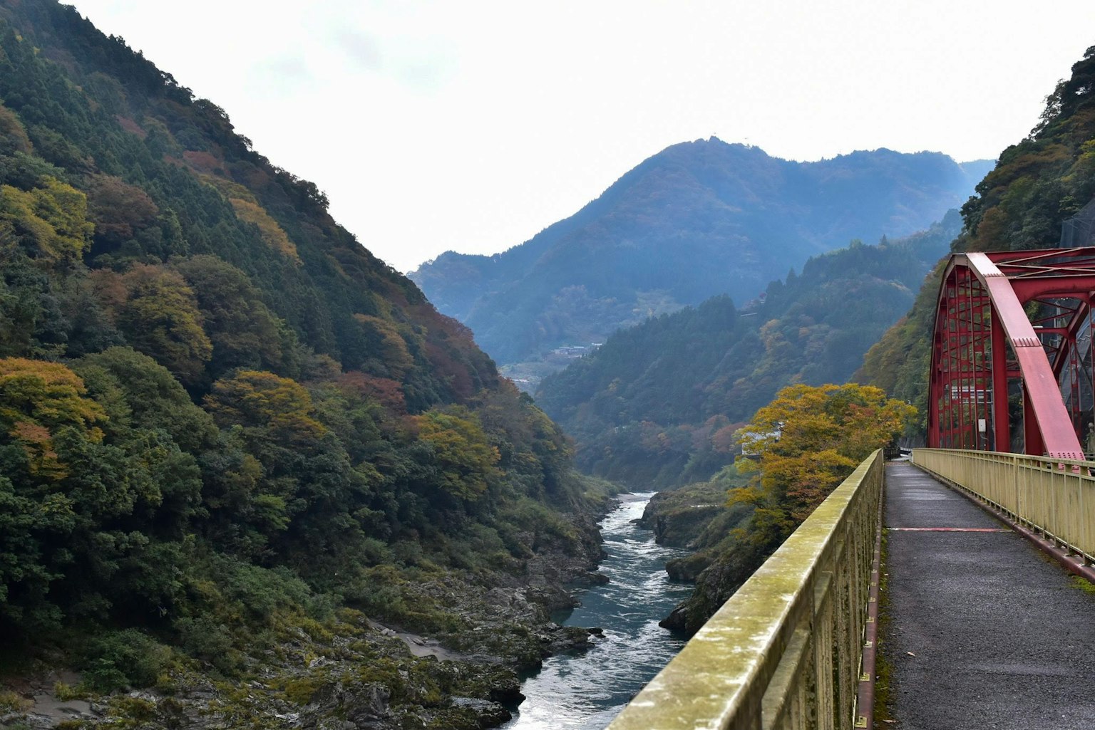 Scenic view of a red bridge over a river surrounded by mountains