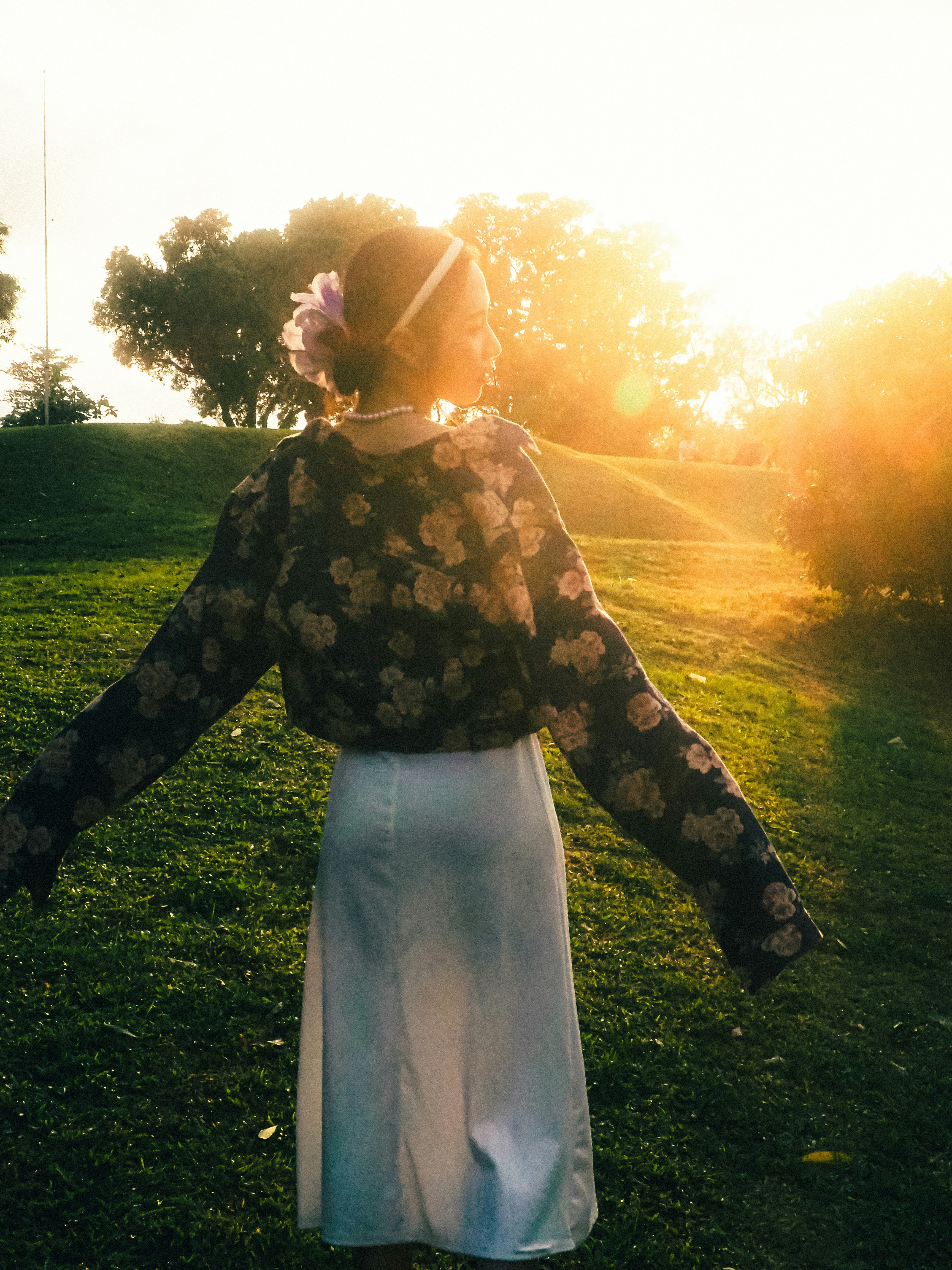 夕暮れの草地で花柄の服を着た女性
