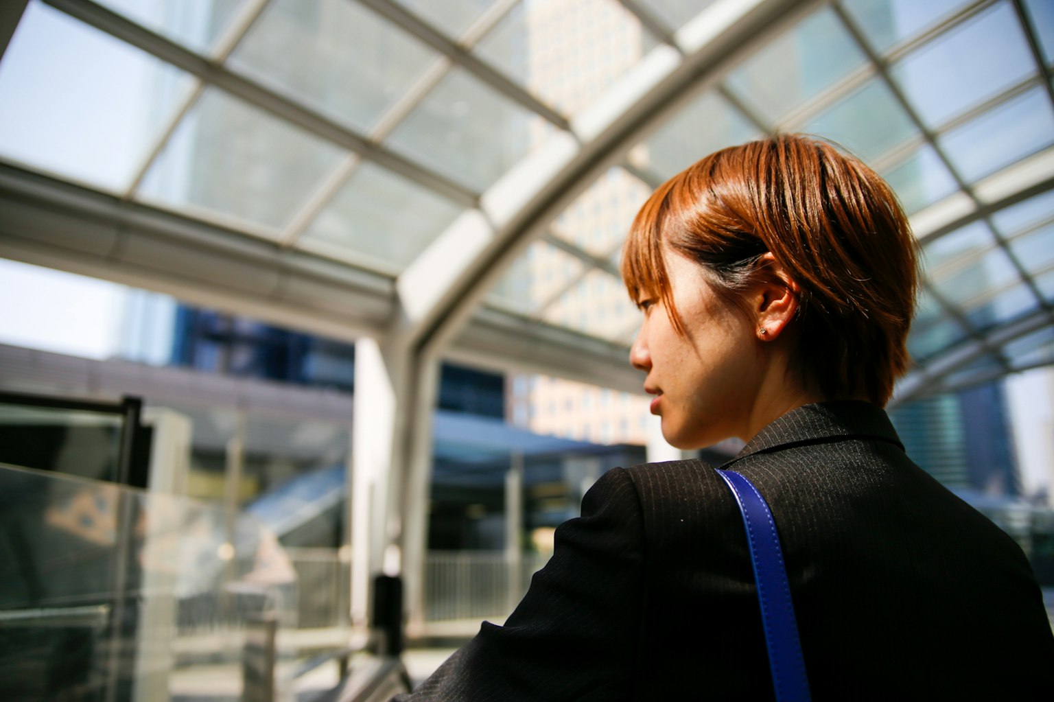 Perfil de una mujer de pie bajo un techo transparente en el interior
