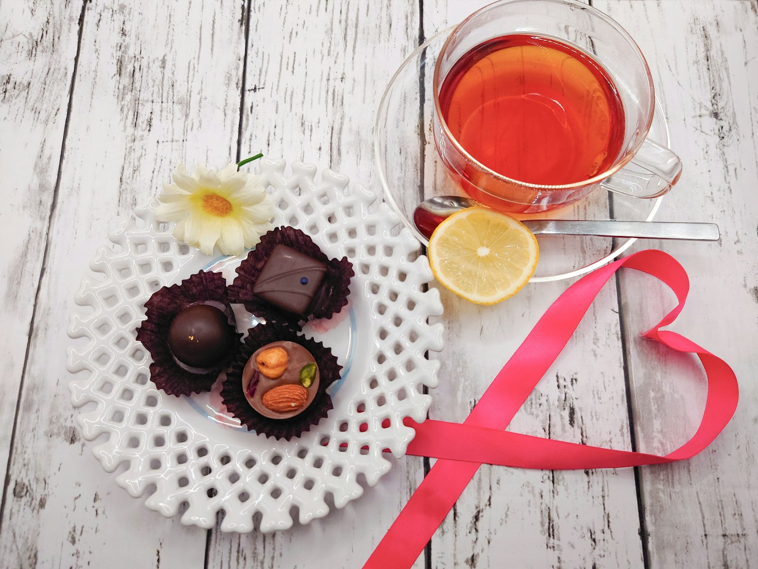 Piatto bianco elegante con cioccolatini assortiti e una tazza di tè