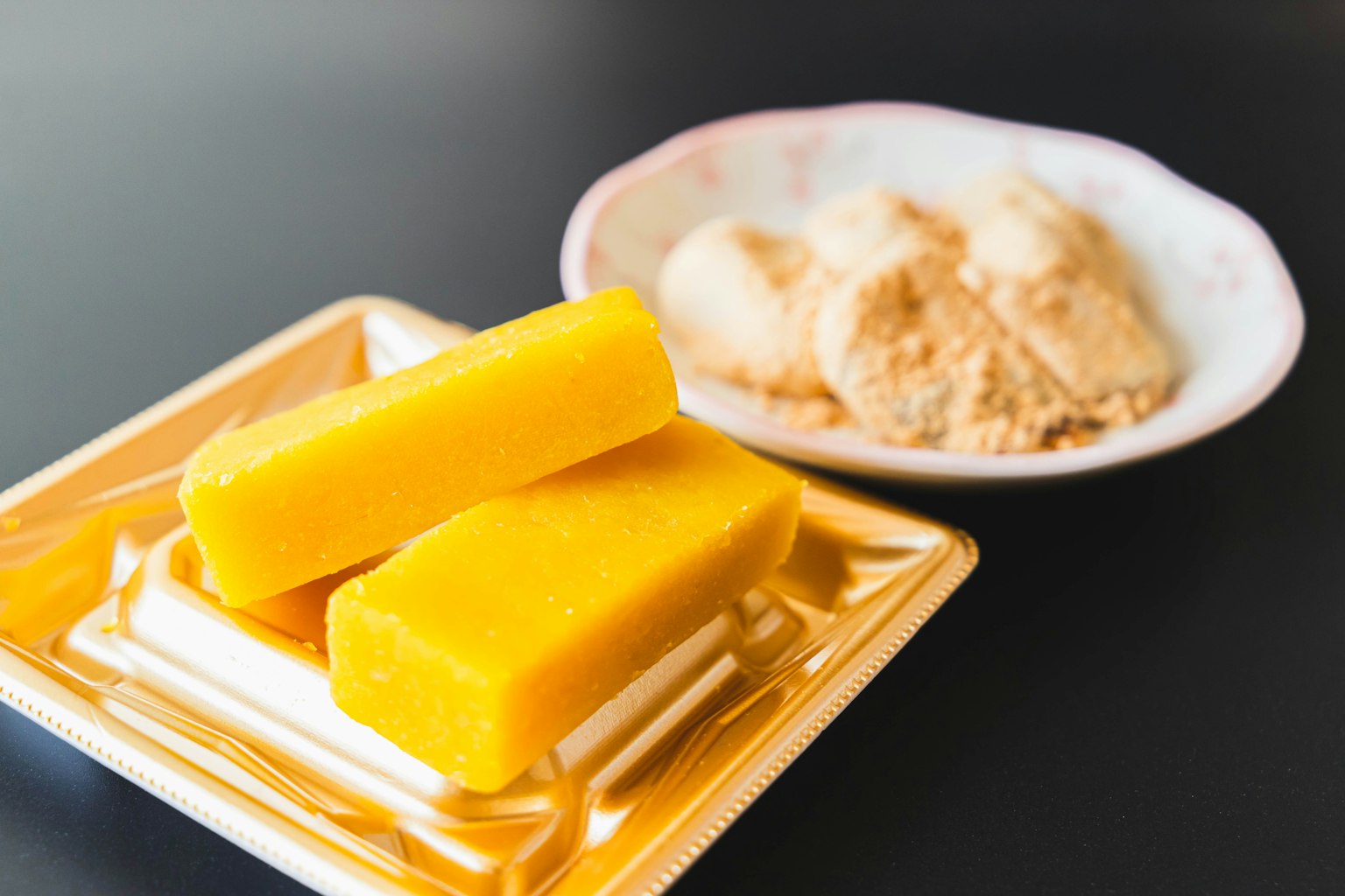 Dolci giapponesi gialli e una ciotola di farina di soia