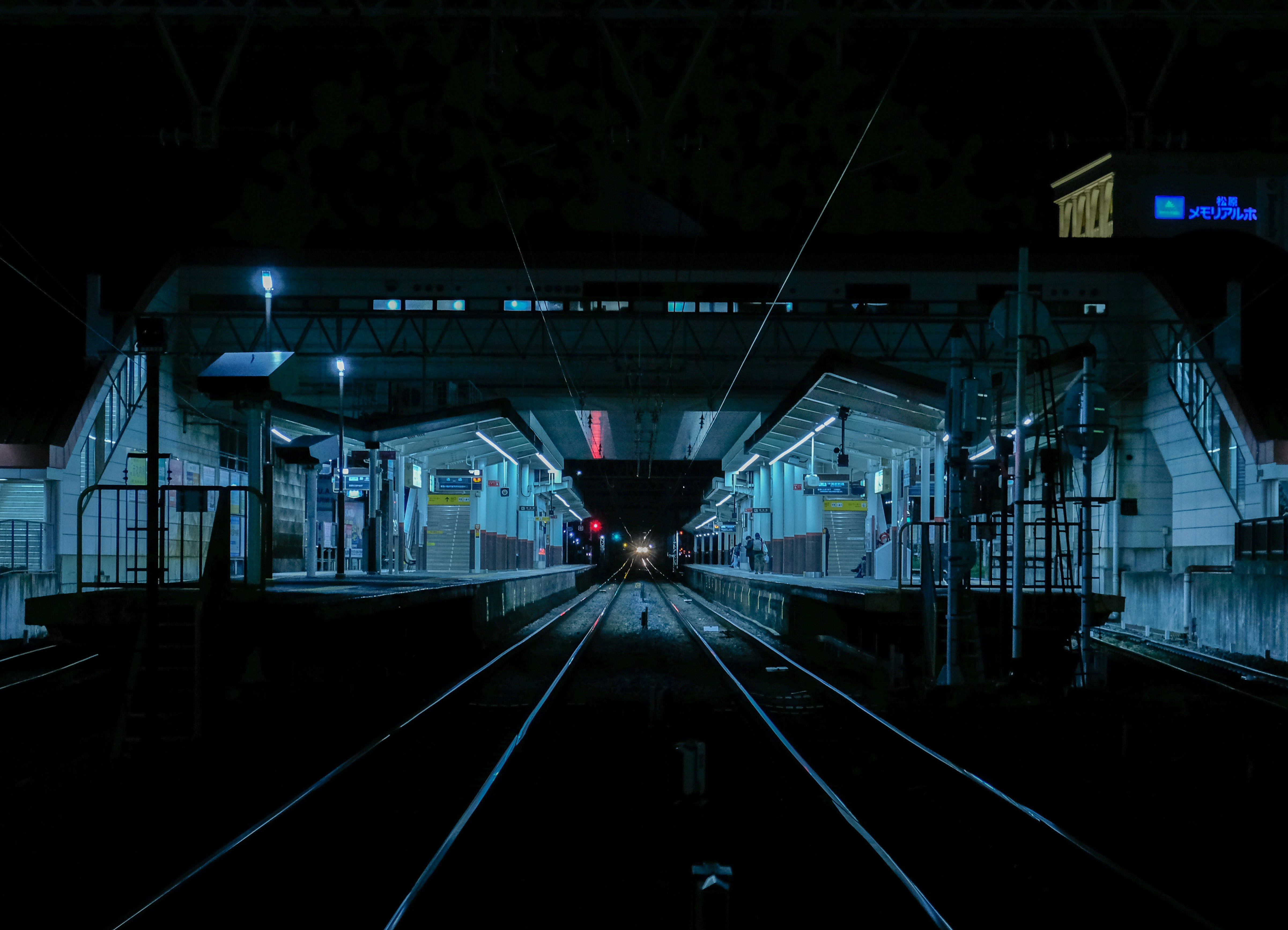 nighttime station platform with tracks stretching into the distance image