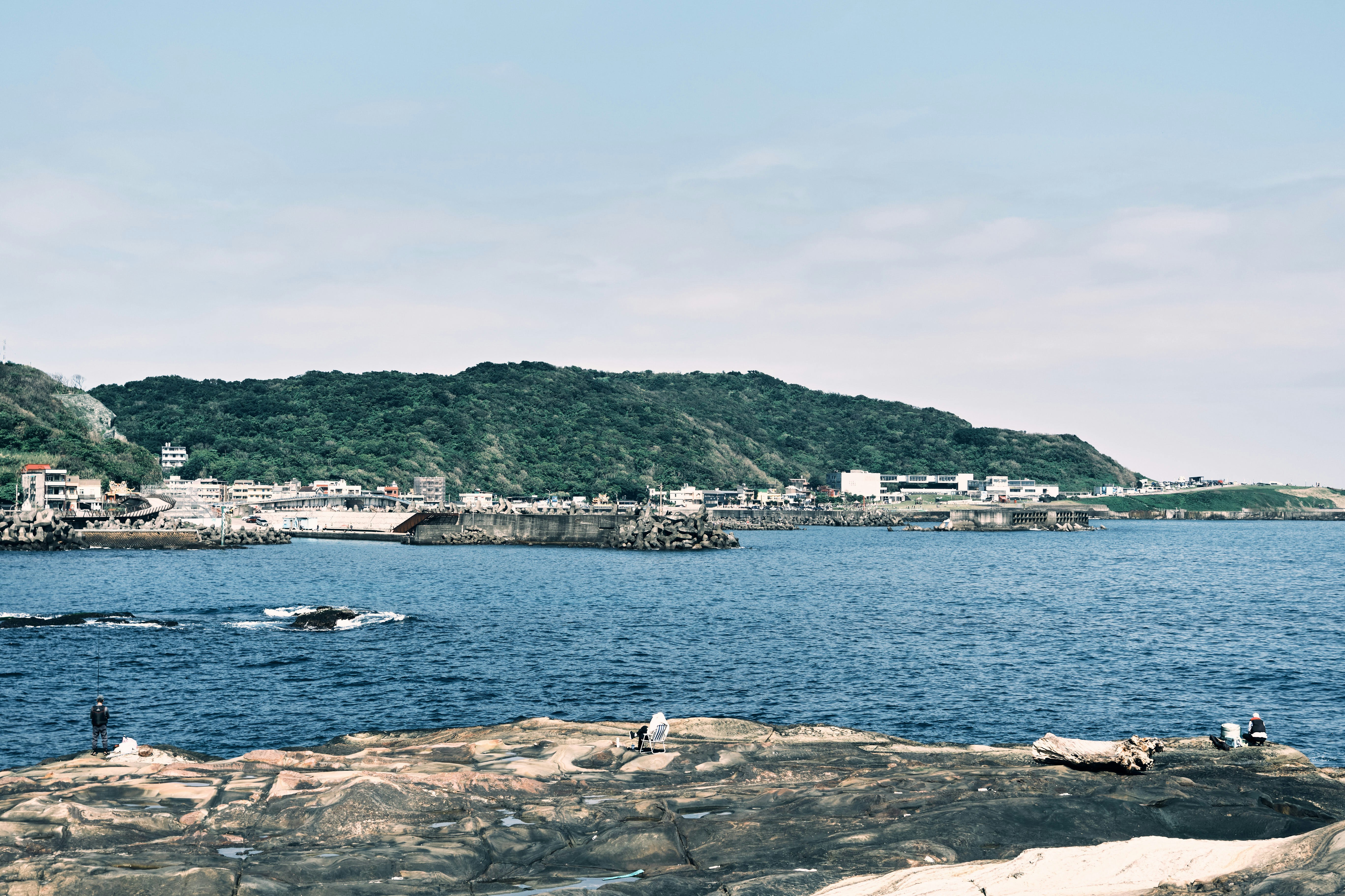 海辺の岩場と穏やかな湾、対岸の街並み