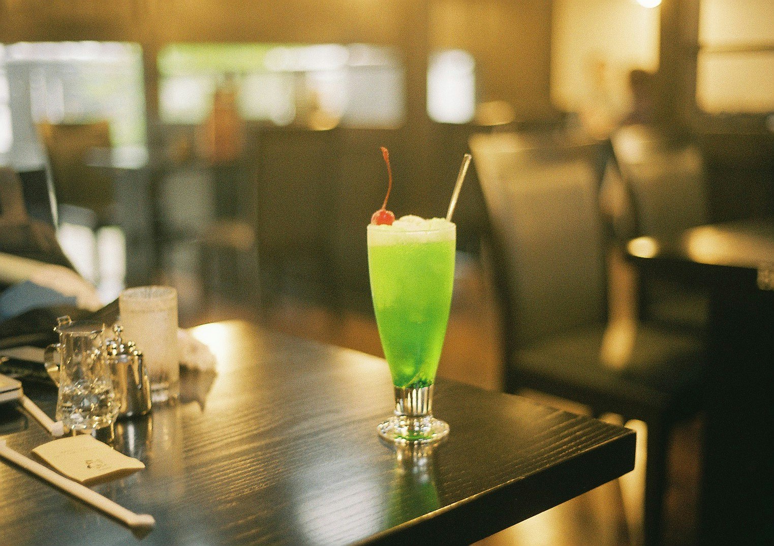 bar interior with a green cocktail on the counter and glasses