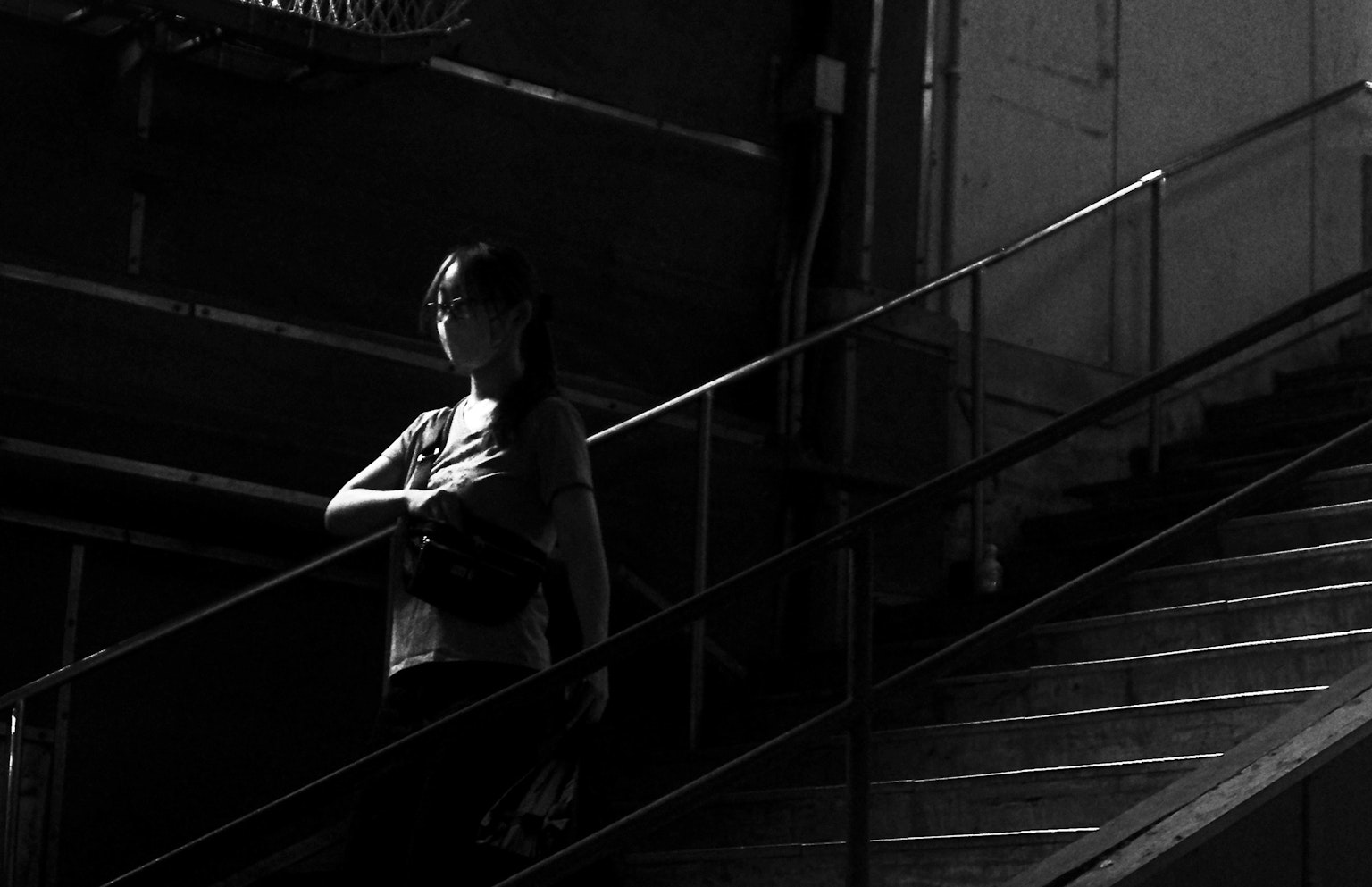 Silhouette of a woman descending stairs in monochrome background with striking lighting contrast