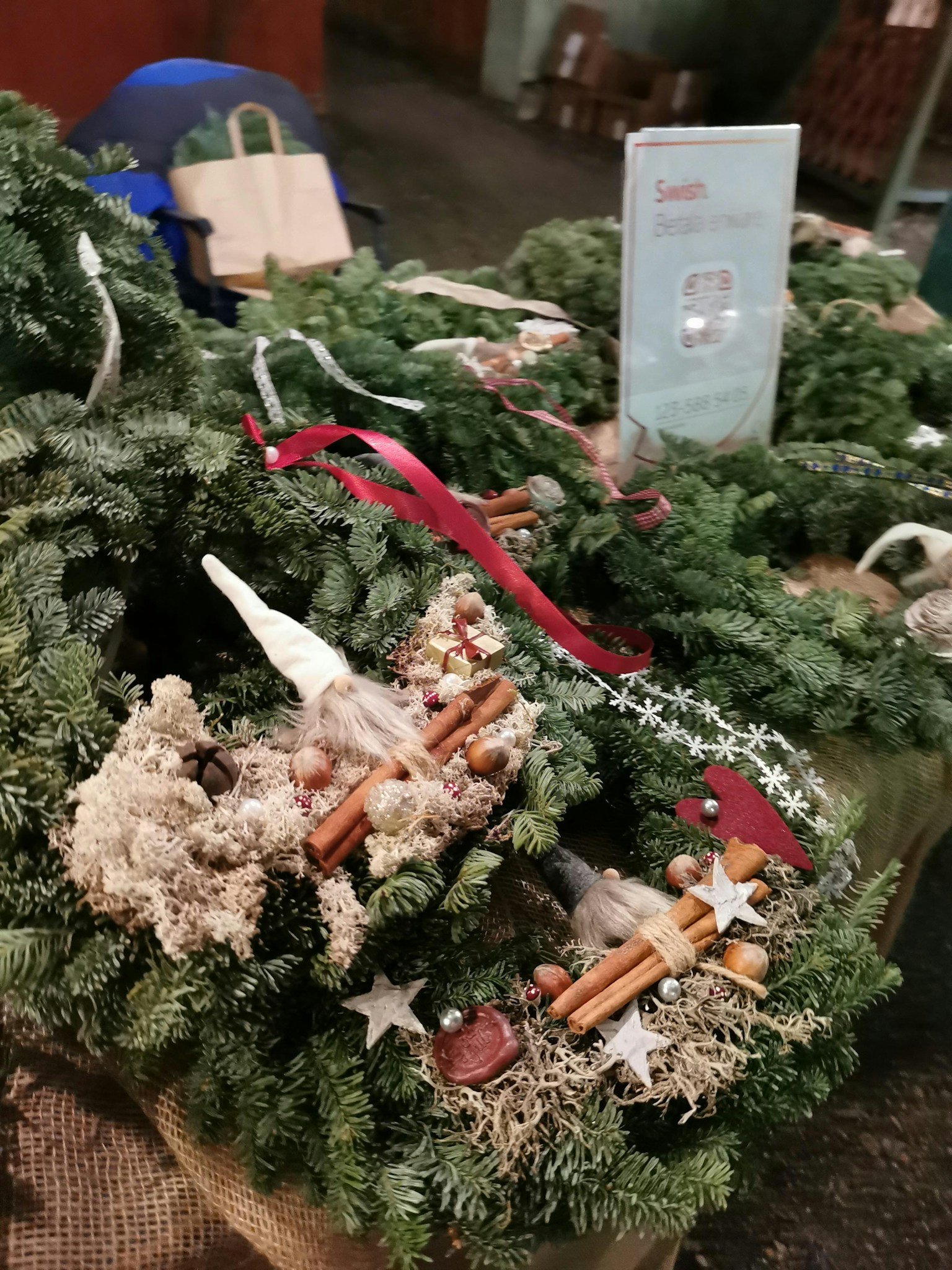 Ausstellung von Weihnachtskränzen mit grünem Laub und roten Bändern
