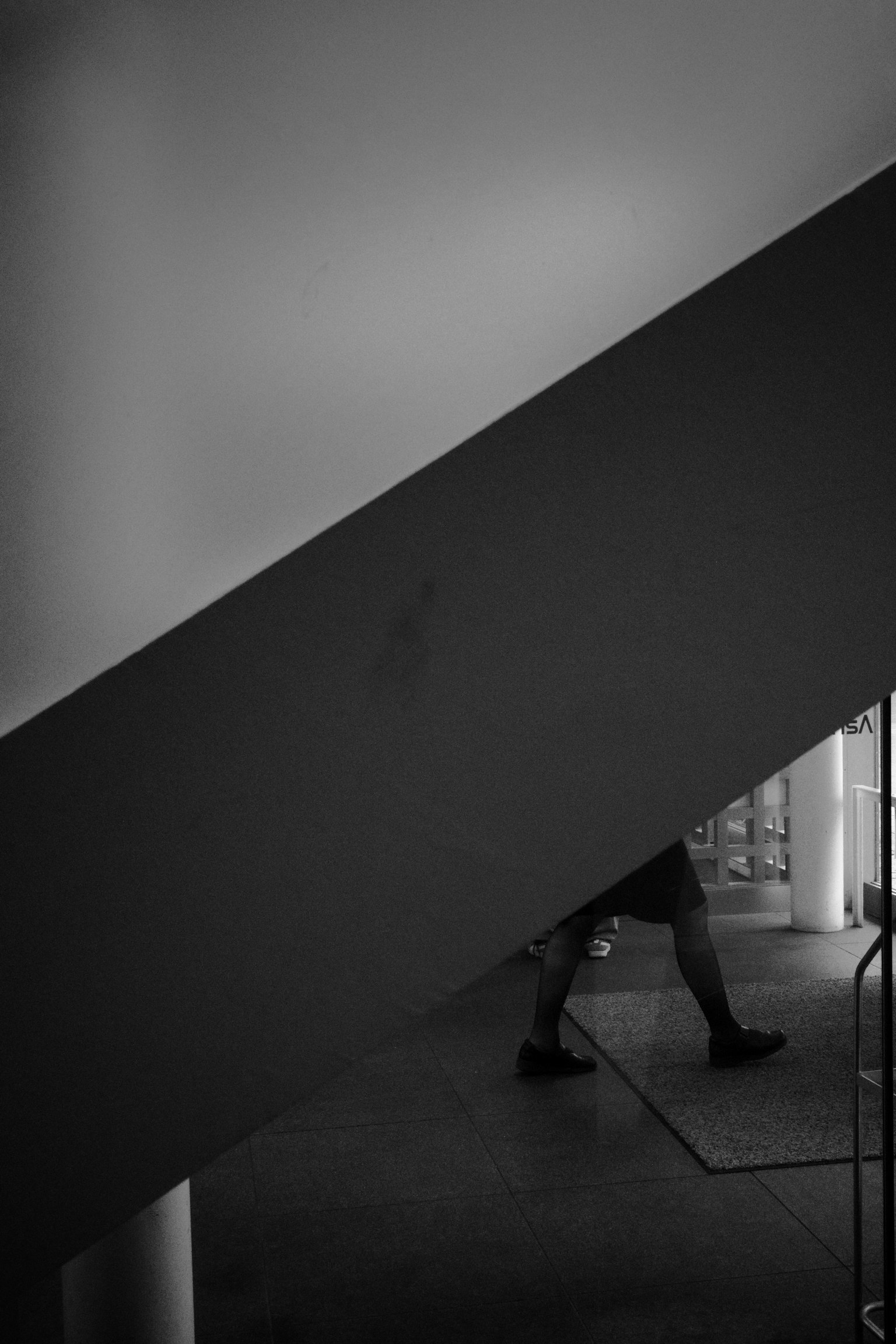 Silhouette einer Person, die unter einer Treppe in einem Schwarzweißbild geht
