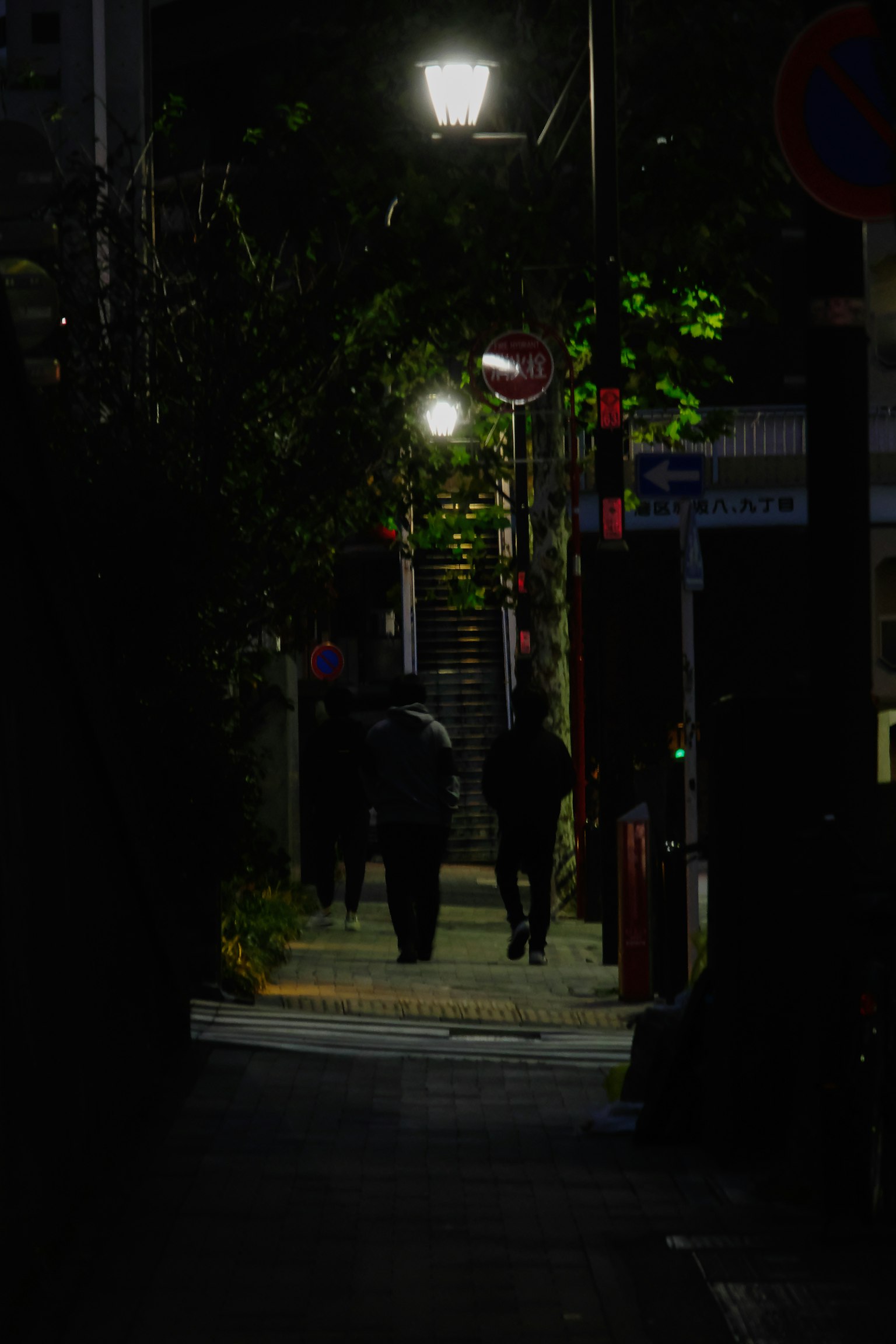 在昏暗街道上行走的行人轮廓与路灯