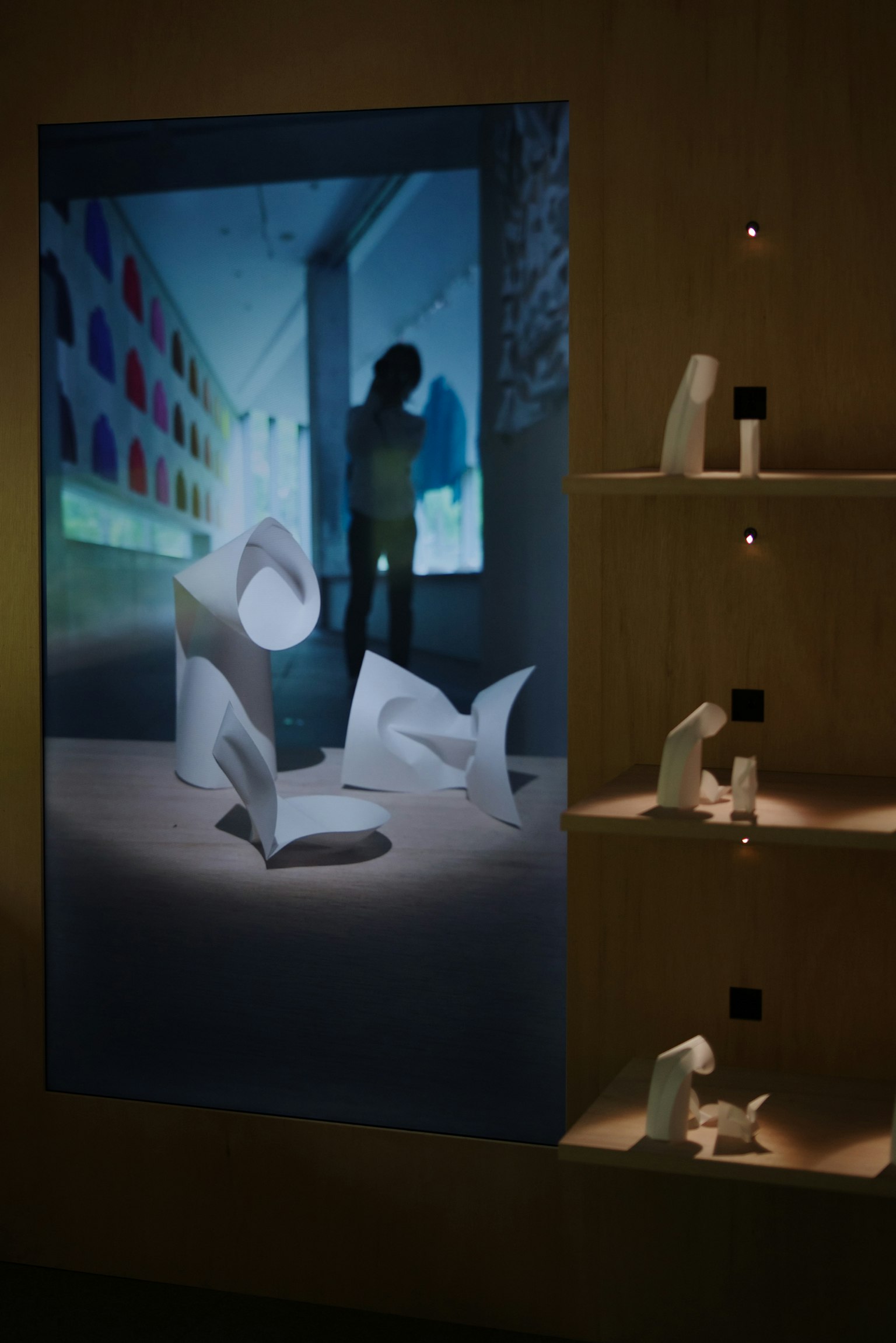 Kunstinstallation mit weißen Papierskulpturen und einer Silhouette im Hintergrund