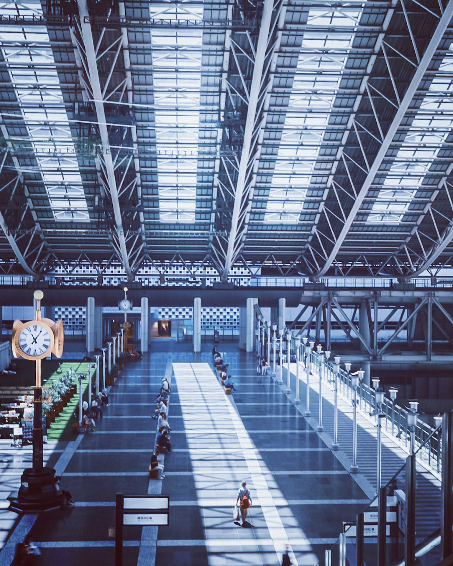 Geräumiger Bahnhof innen mit großem Glasdach und Lichtstrahlen Uhrturm als Merkmal