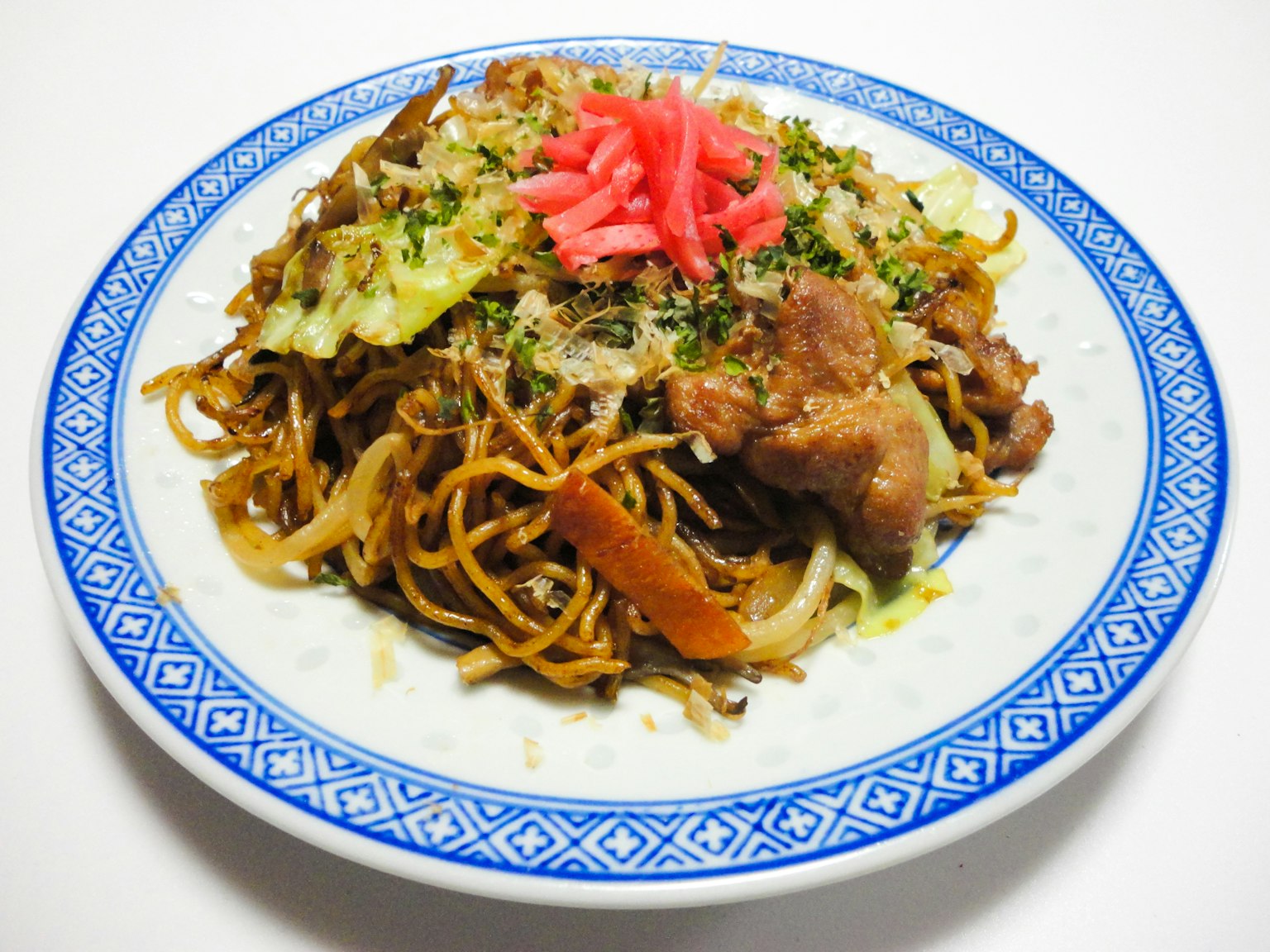 A plate of yakisoba topped with pickled ginger and aonori