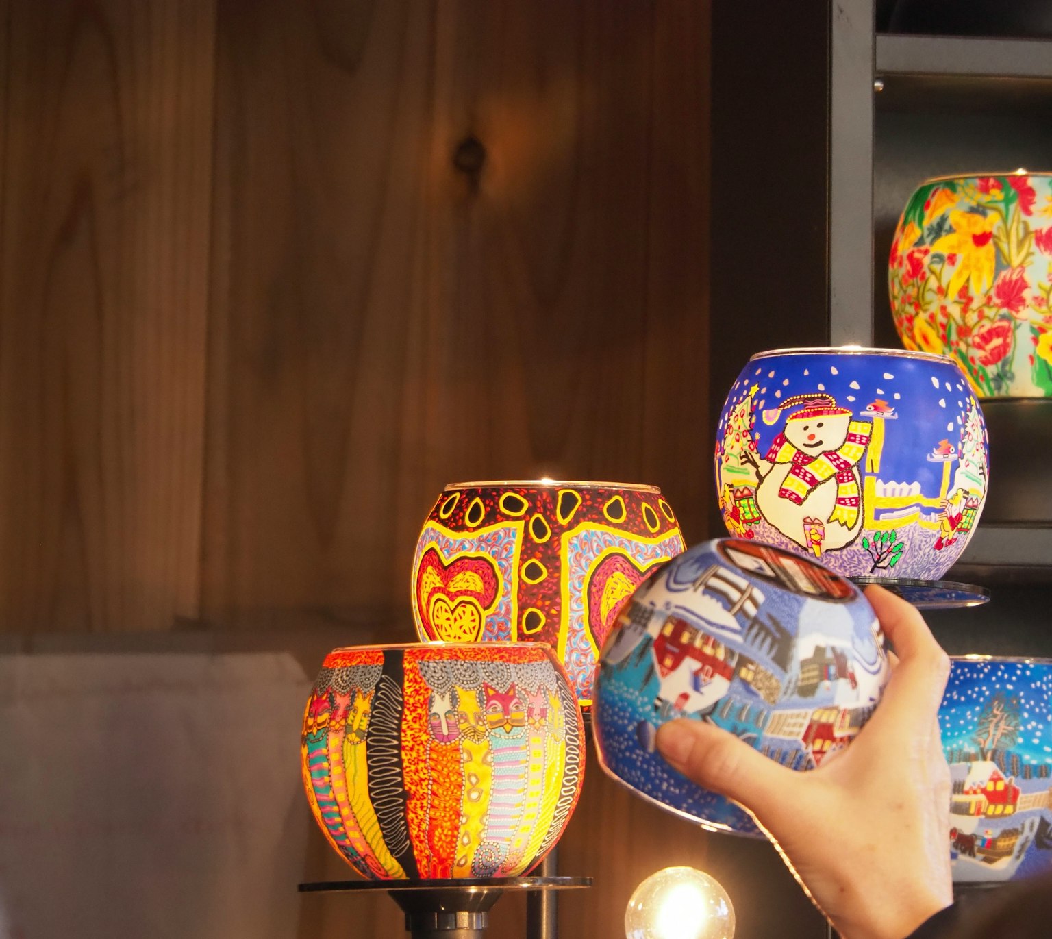 Người đang cầm những chiếc bát gốm sứ trang trí nhiều màu sắc với các thiết kế khác nhau