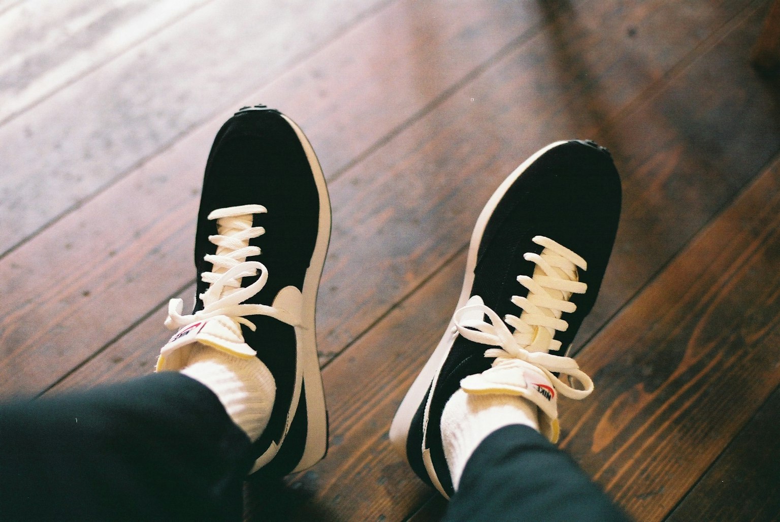 Zapatillas negras y blancas sobre un suelo de madera