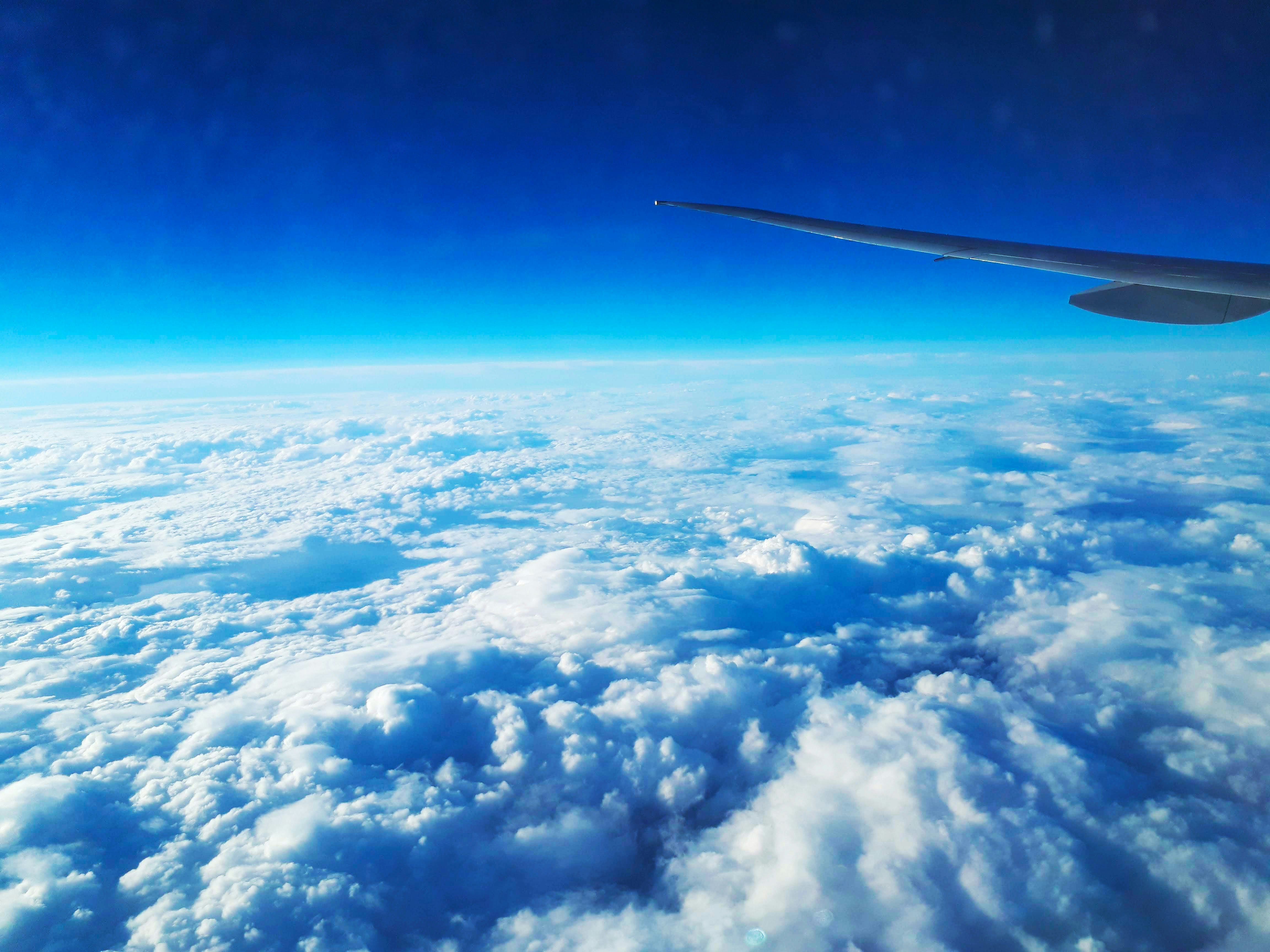 飛行機の窓から見た青空と雲の上の宇宙感