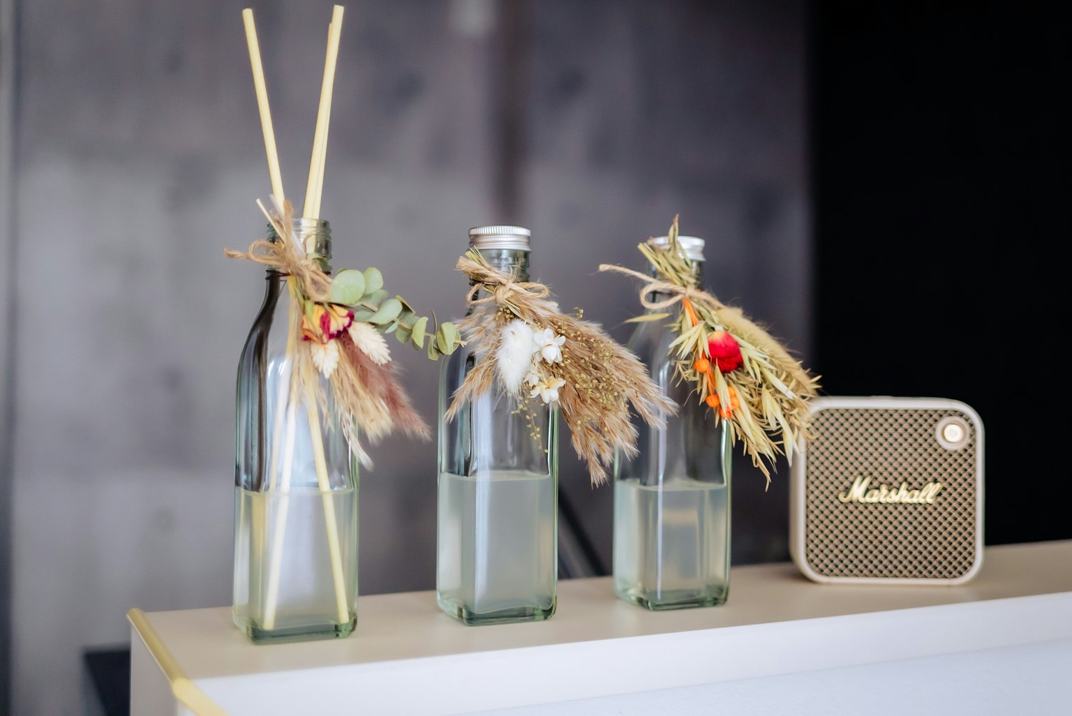 Decorative glass bottles with dried flowers and a Marshall speaker