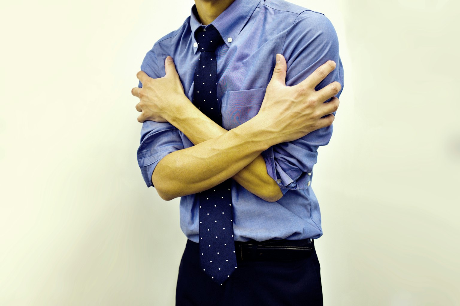 Uomo in camicia blu che si abbraccia con le braccia incrociate