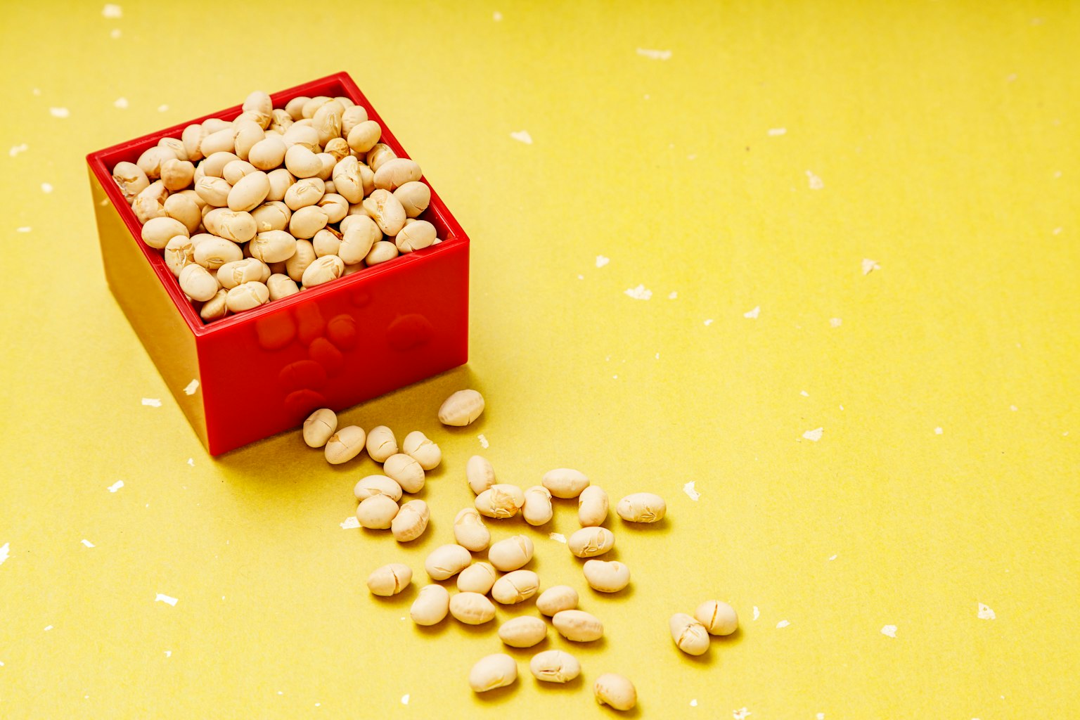 Kacang putih yang tumpah dari kotak merah di atas latar belakang kuning