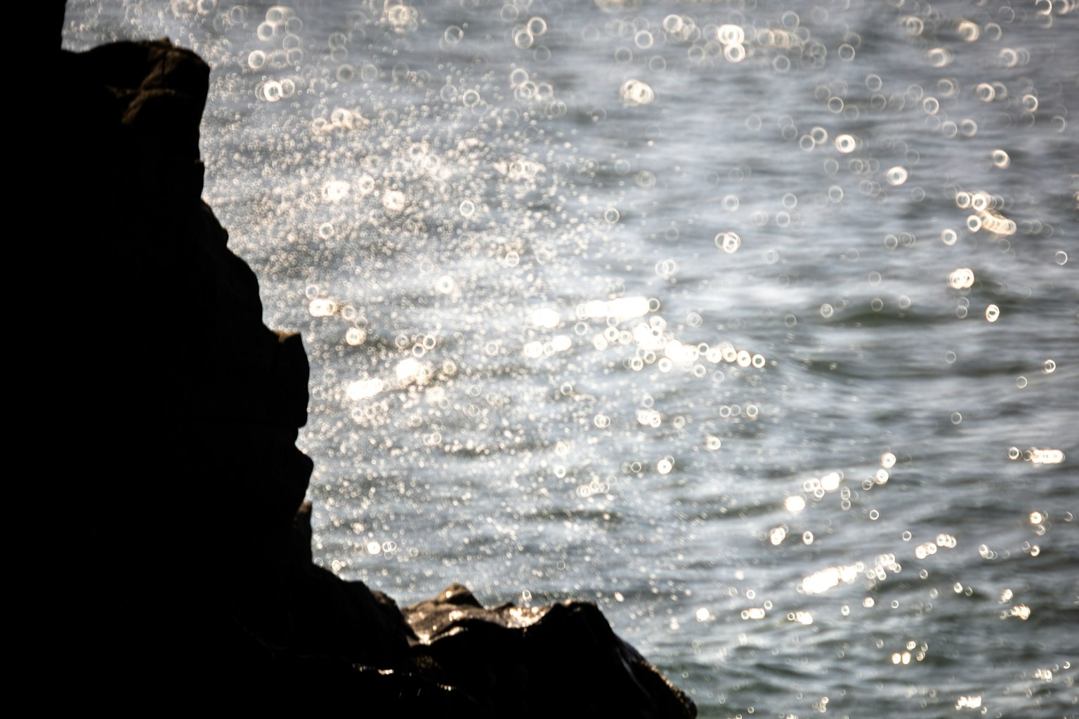 Silhouette di una roccia con onde d'acqua scintillanti