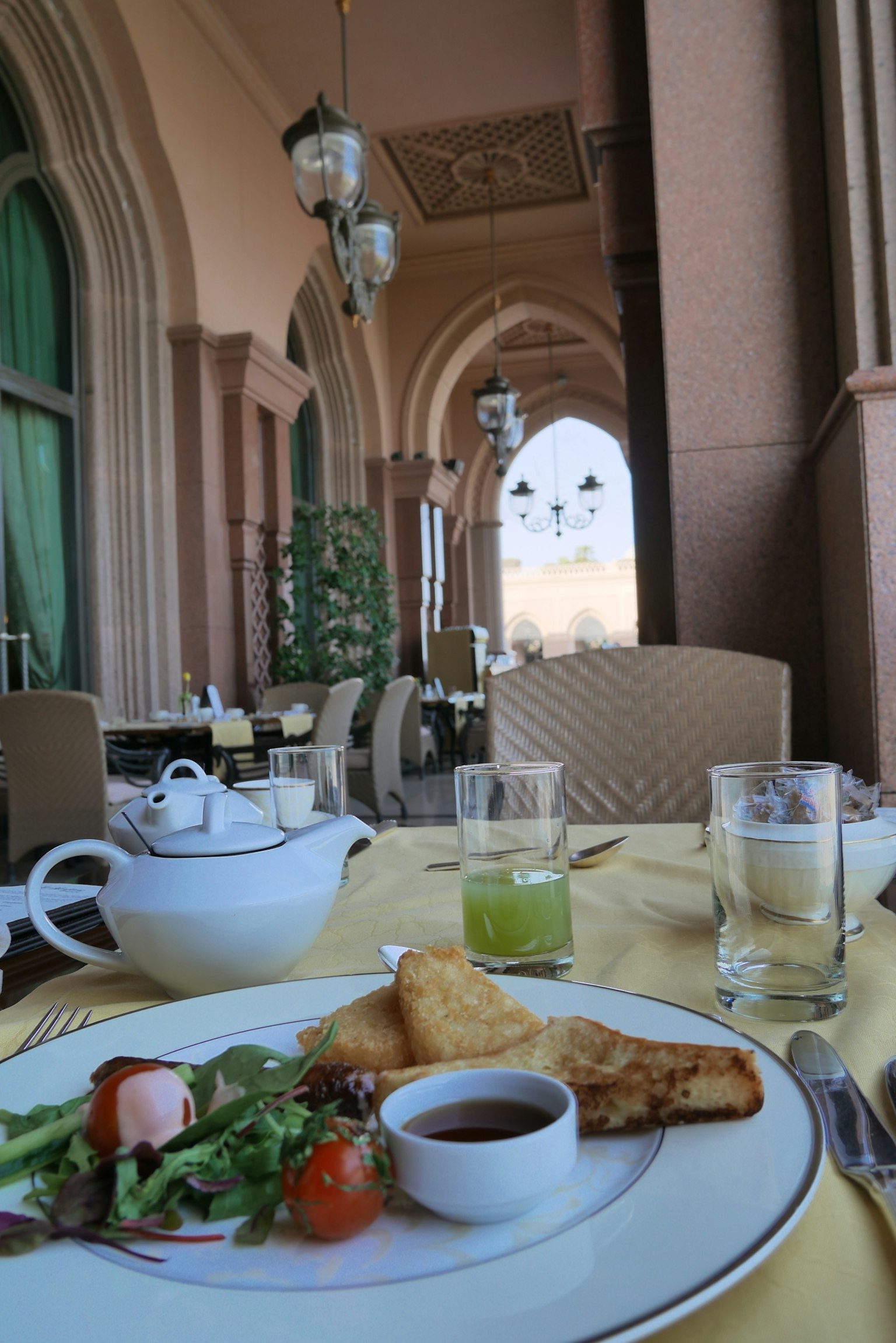 Breakfast scene on a terrace featuring plated food and drinks with beautiful architectural background