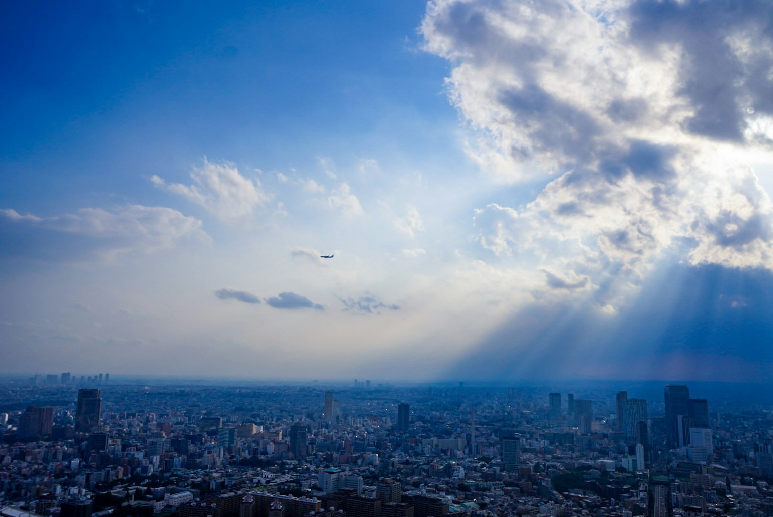 Panorama urbano sotto un cielo blu con nuvole e raggi di sole
