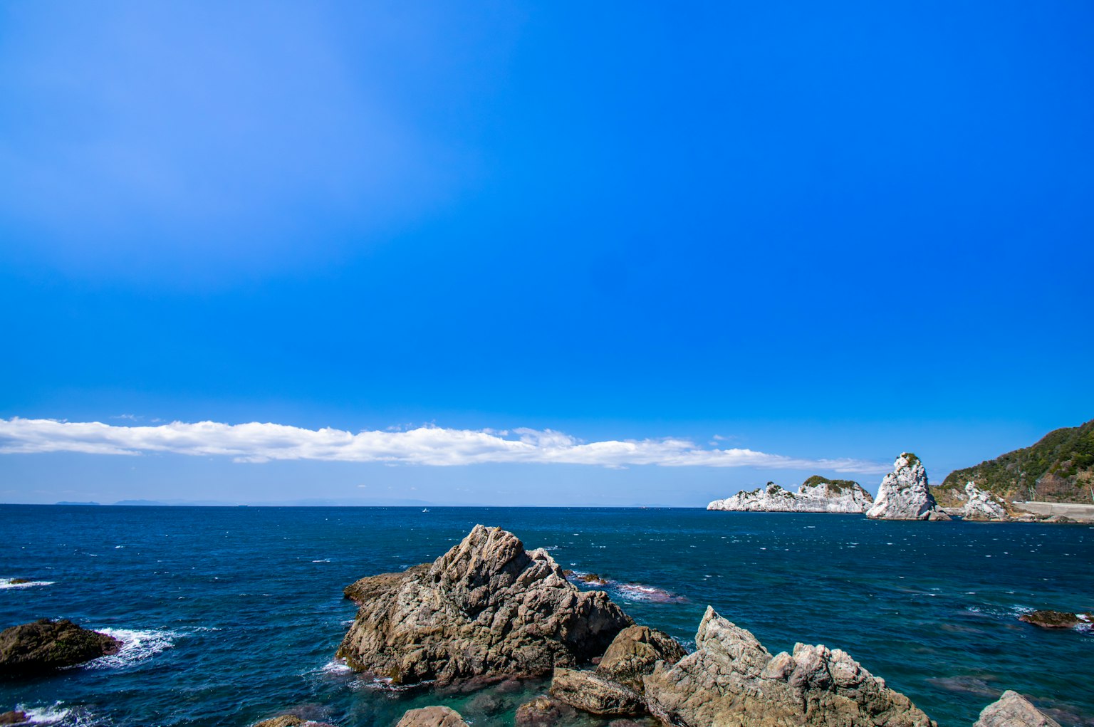 Scenic view of blue sky and ocean with visible rocks and waves