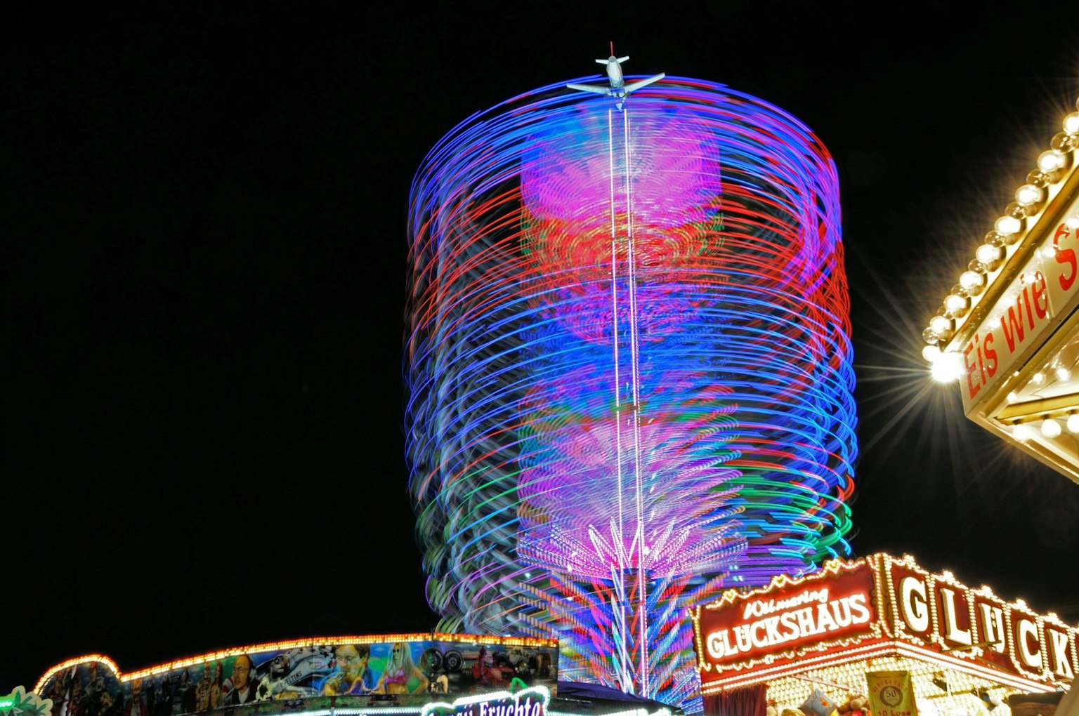 Bunte beleuchtete Turm in der Nacht mit lebhaften Lichtern und Jahrmarktschildern