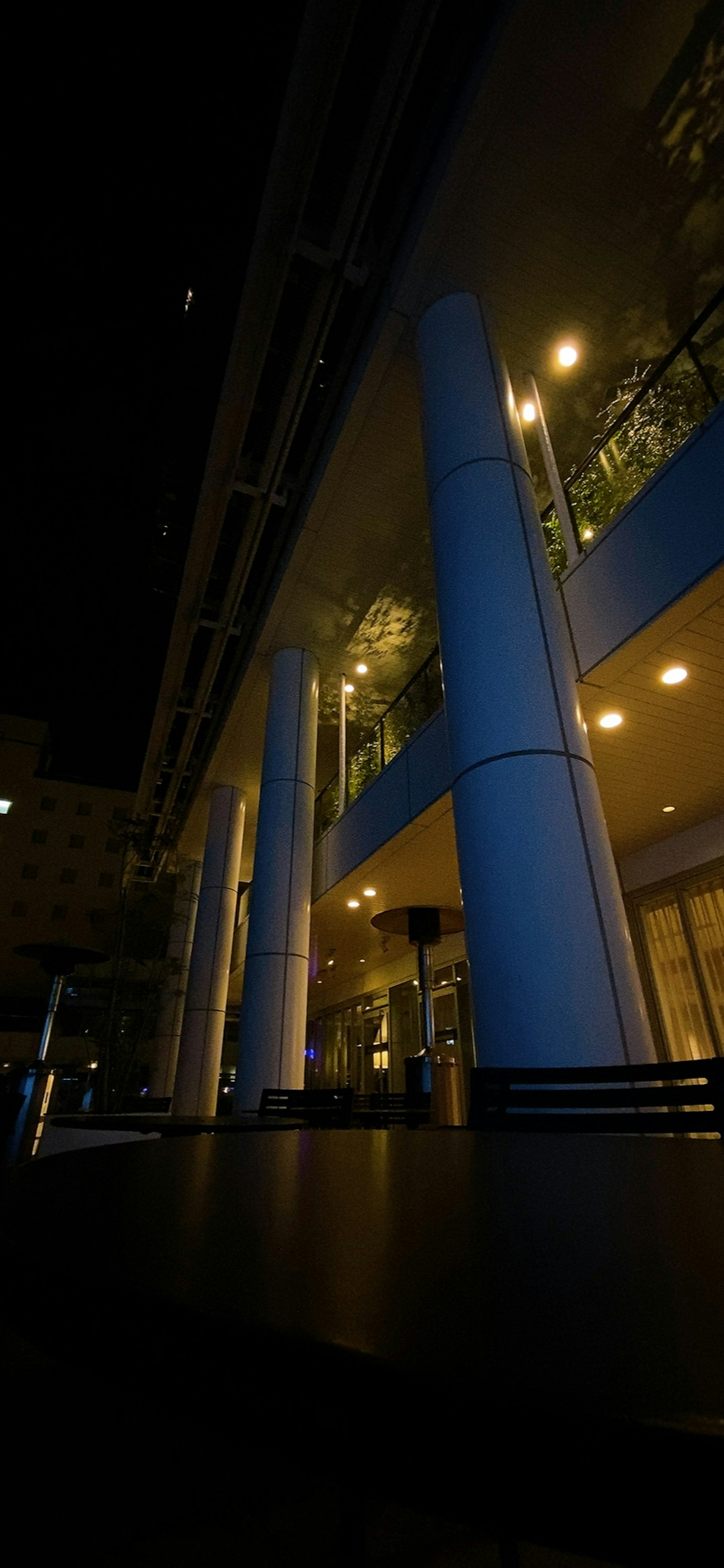 Esterno di un edificio cittadino di notte con colonne blu e illuminazione calda
