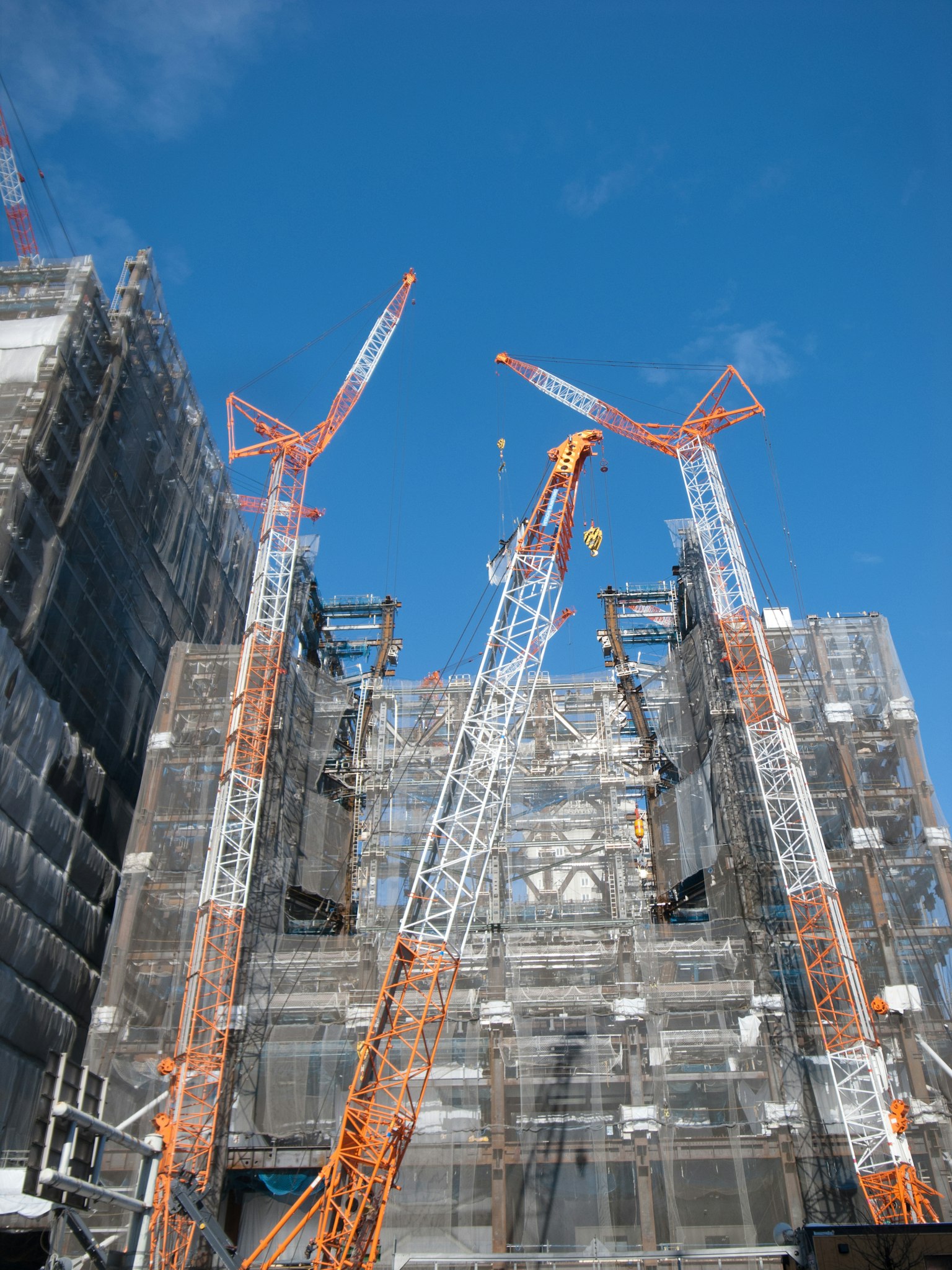 Situs konstruksi dengan crane dan gedung di bawah langit biru