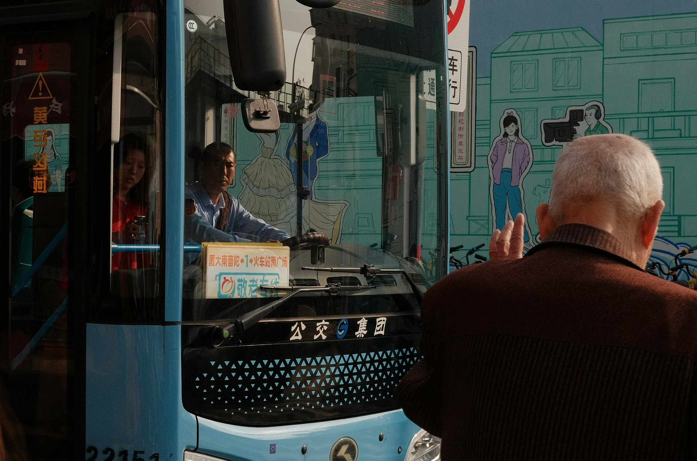車内の運転席付近で高齢の乗客が前方を見ている
