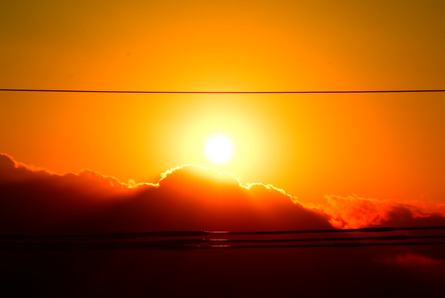 電線に挟まれる夕陽と雲のシルエット