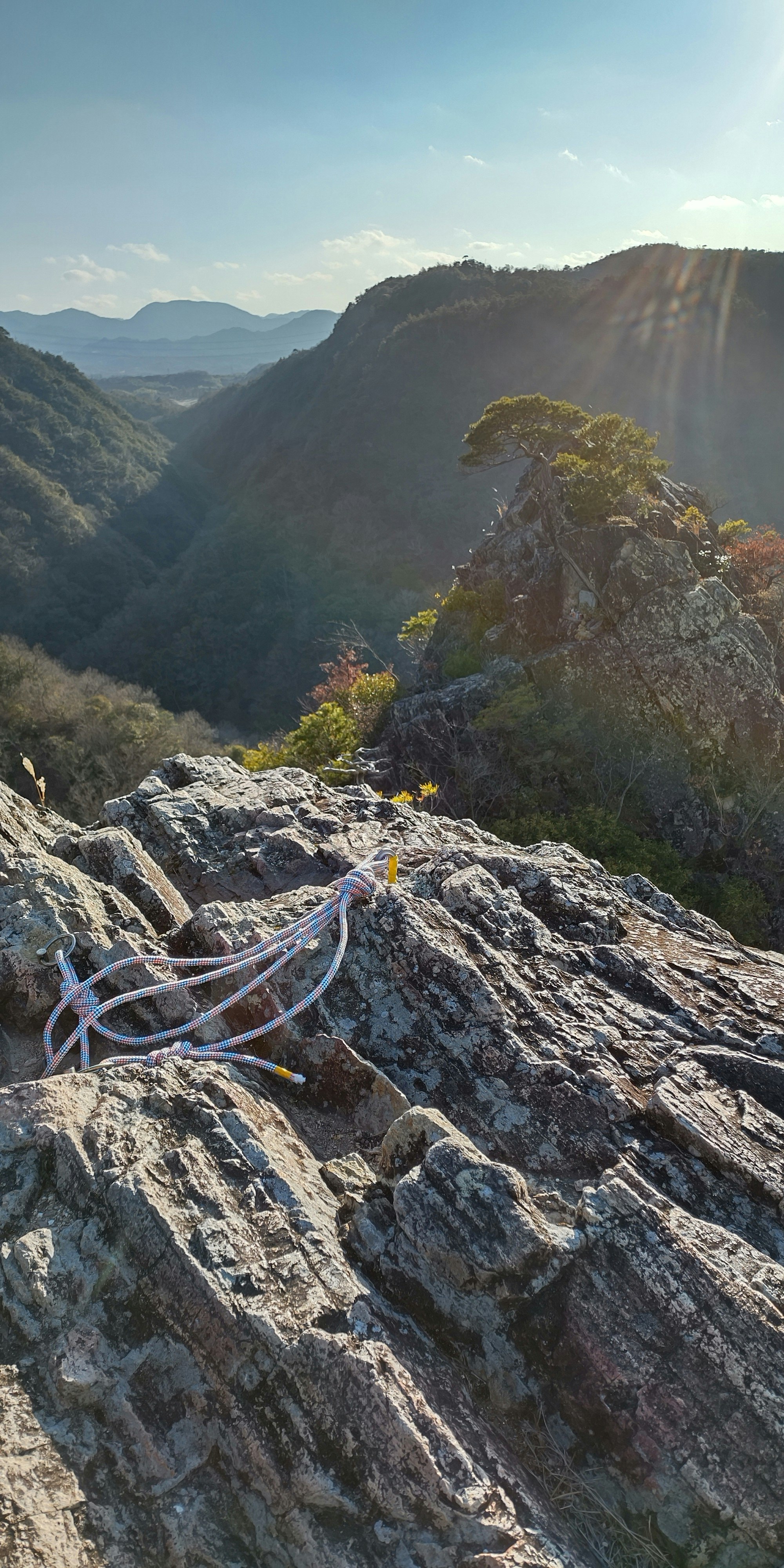岩山の稜線から見渡す山並みとロープのある登山道