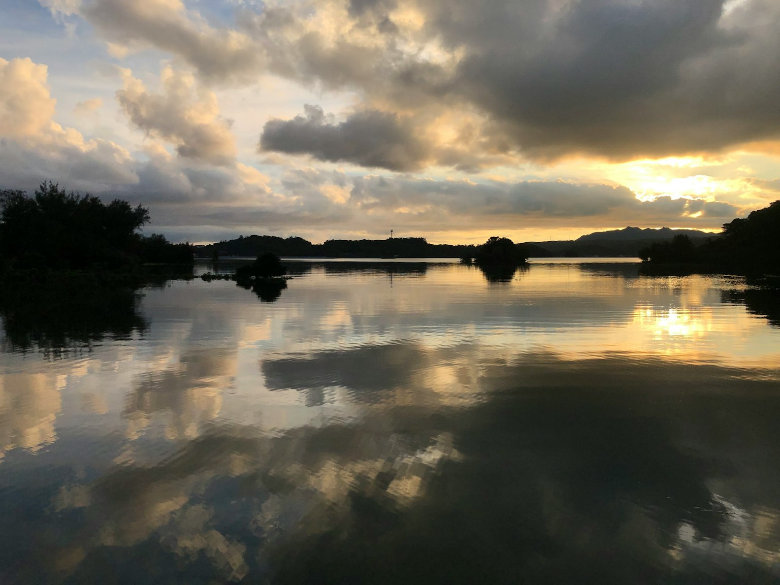 Lago sereno che riflette nuvole e tramonto, paesaggio tranquillo