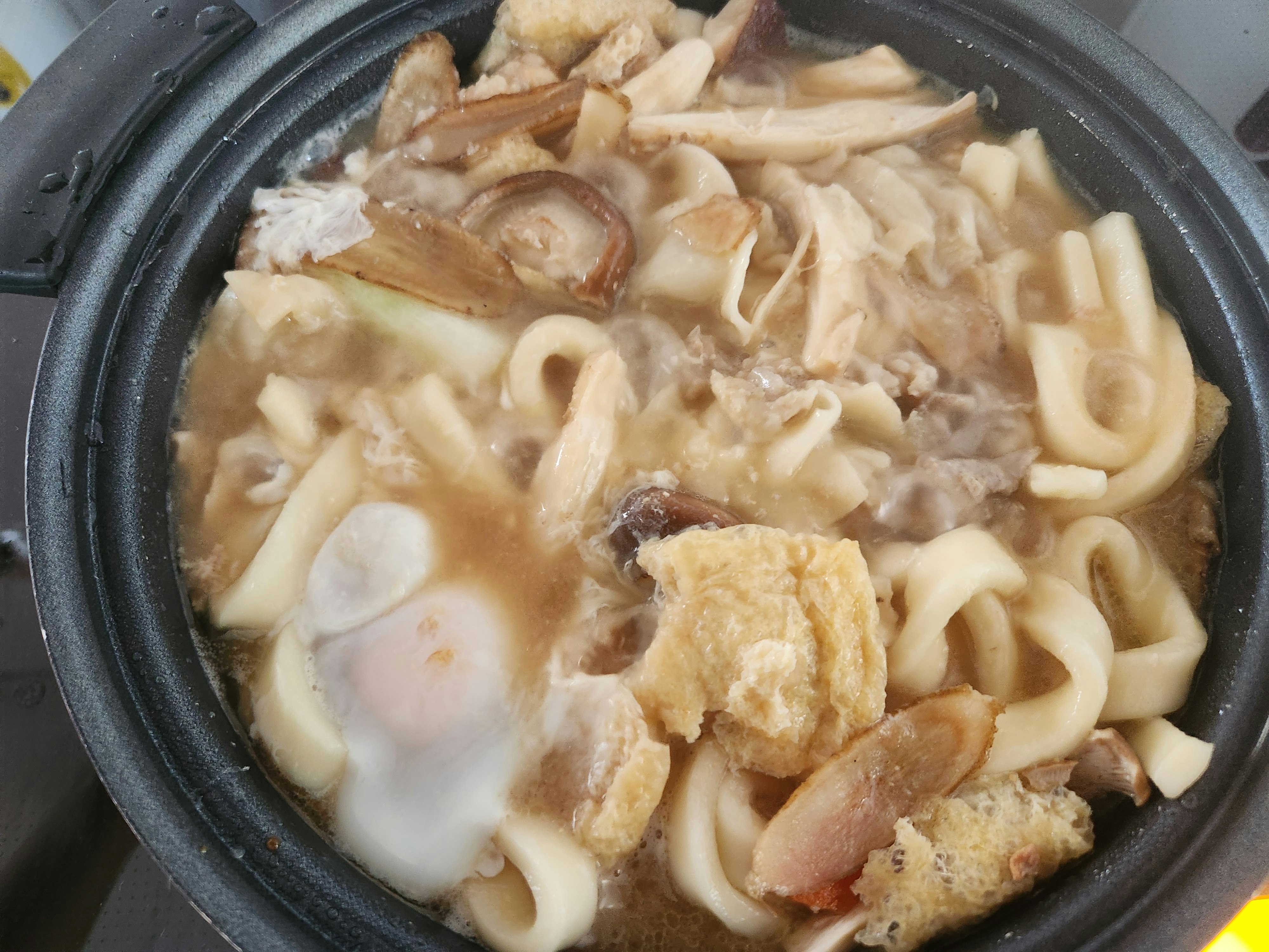 鍋で煮込まれたうどんと具材の入った一皿