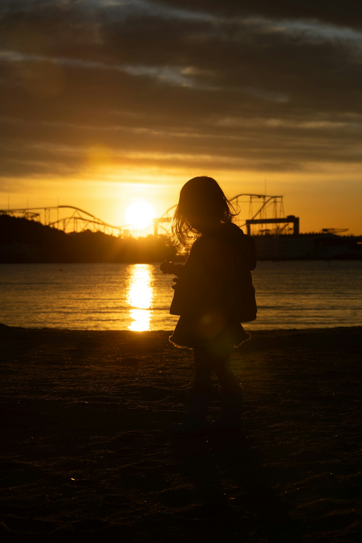 Silhouette d'une femme se tenant sur la plage avec un coucher de soleil en arrière-plan