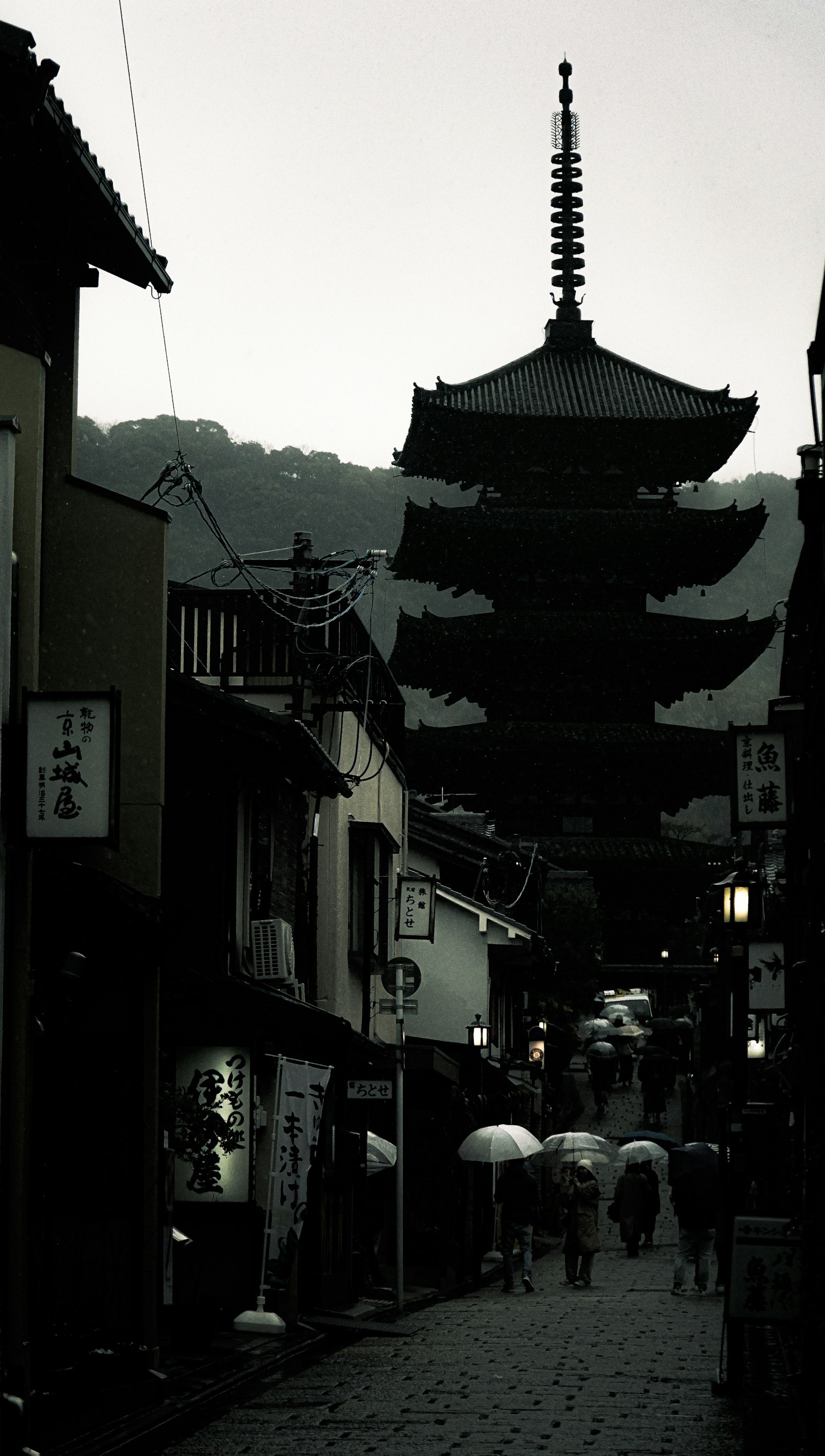 京都五重塔的輪廓，雨天人們撐著傘
