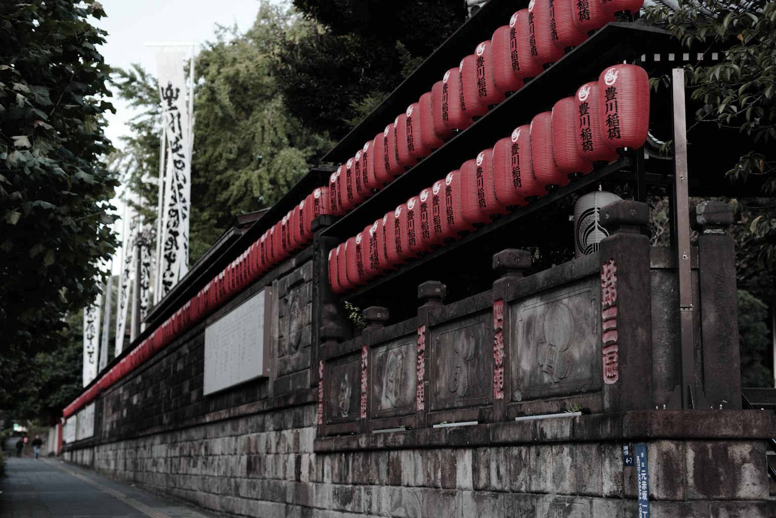 ทิวทัศน์ของโคมไฟแดงเรียงรายตามกำแพงหินเก่า