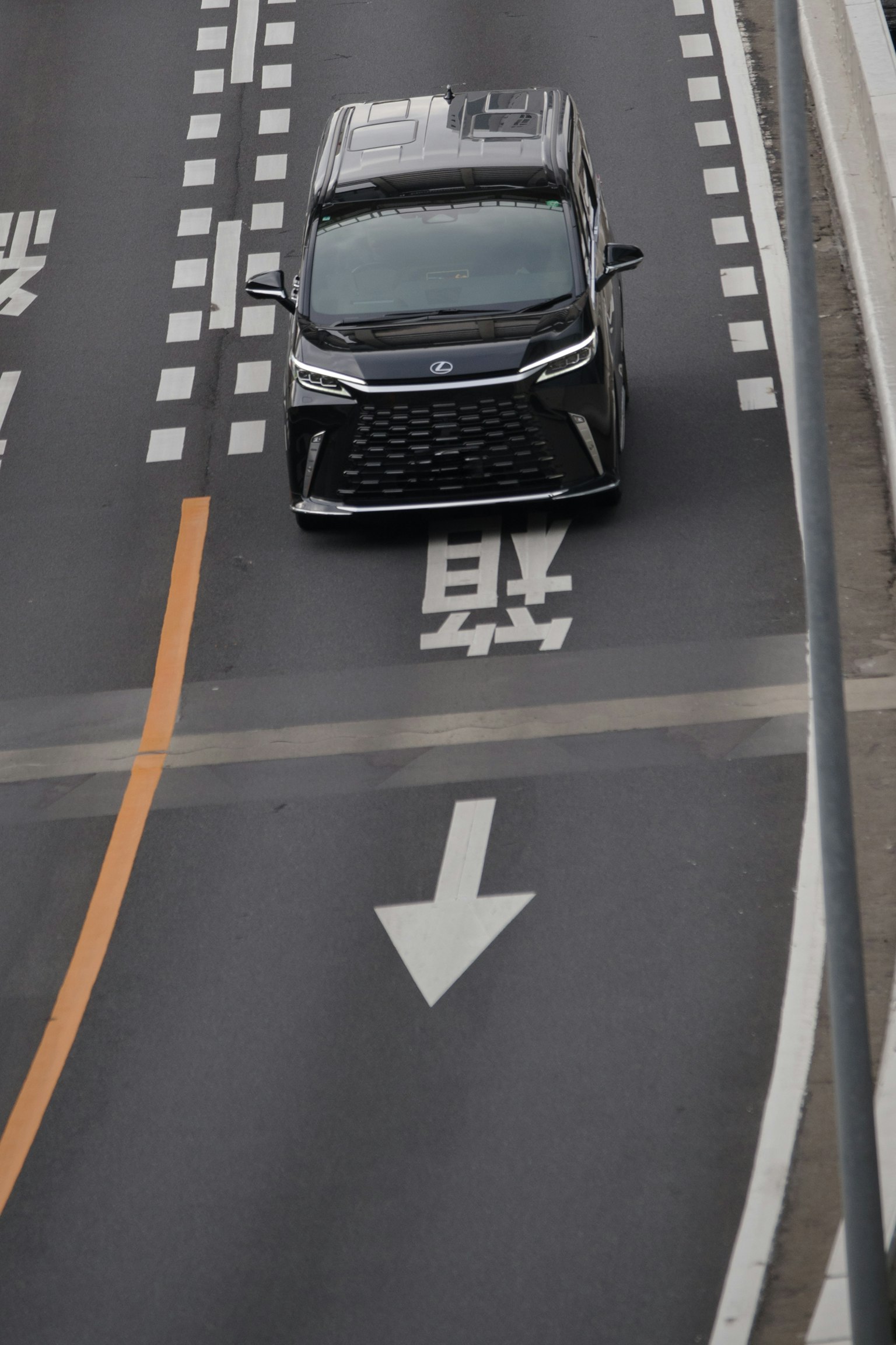Un'auto nera che guida su una strada con segnaletica direzionale