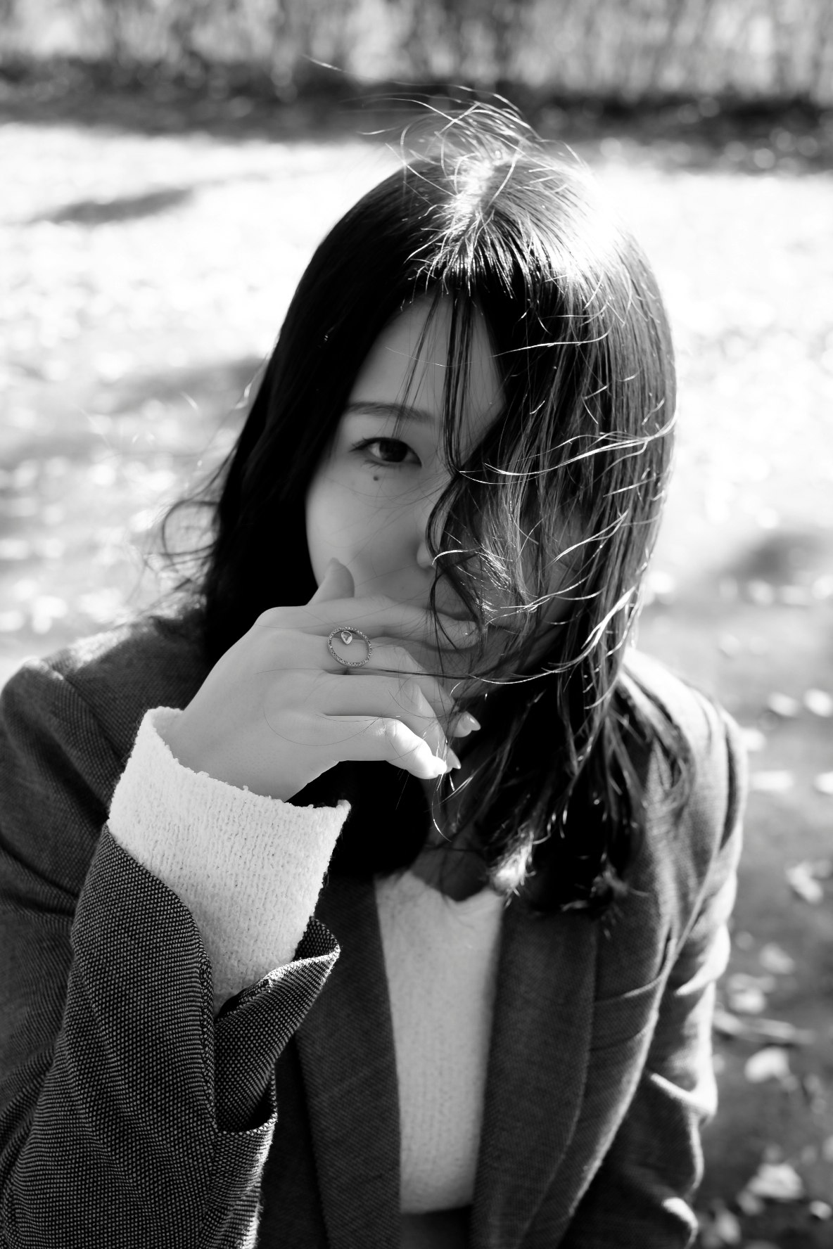 女性が手で口元を隠しながら見つめるモノクロ写真