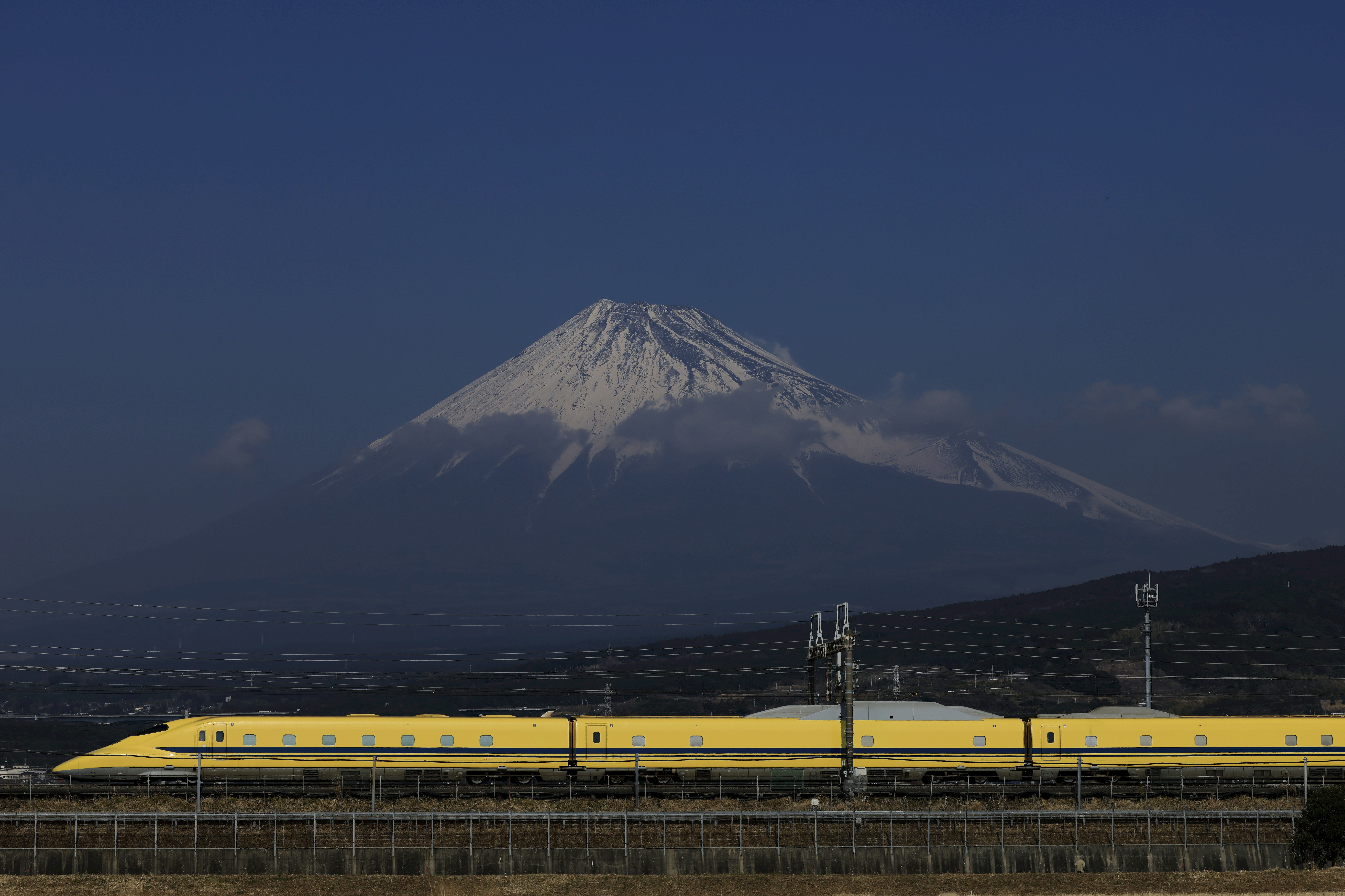 ドクターイエローの車両が富士山を背景に走る風景