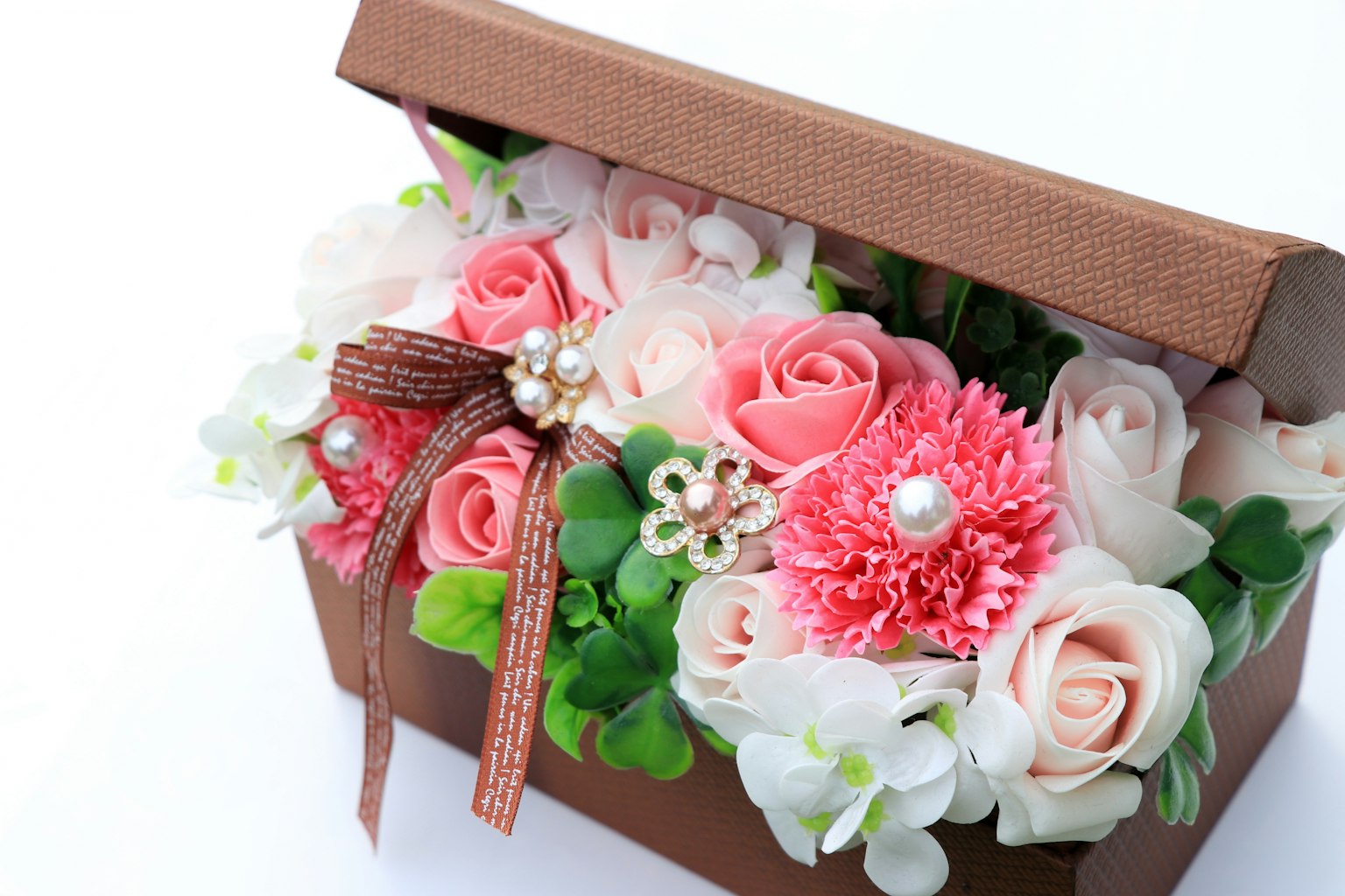 Composizione in scatola marrone con rose rosa e fiori bianchi