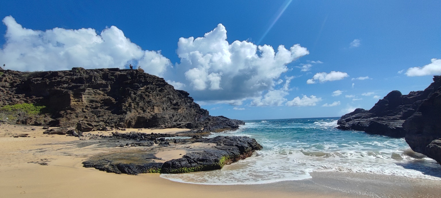Pemandangan pantai yang indah dengan langit biru awan putih batu dan ombak