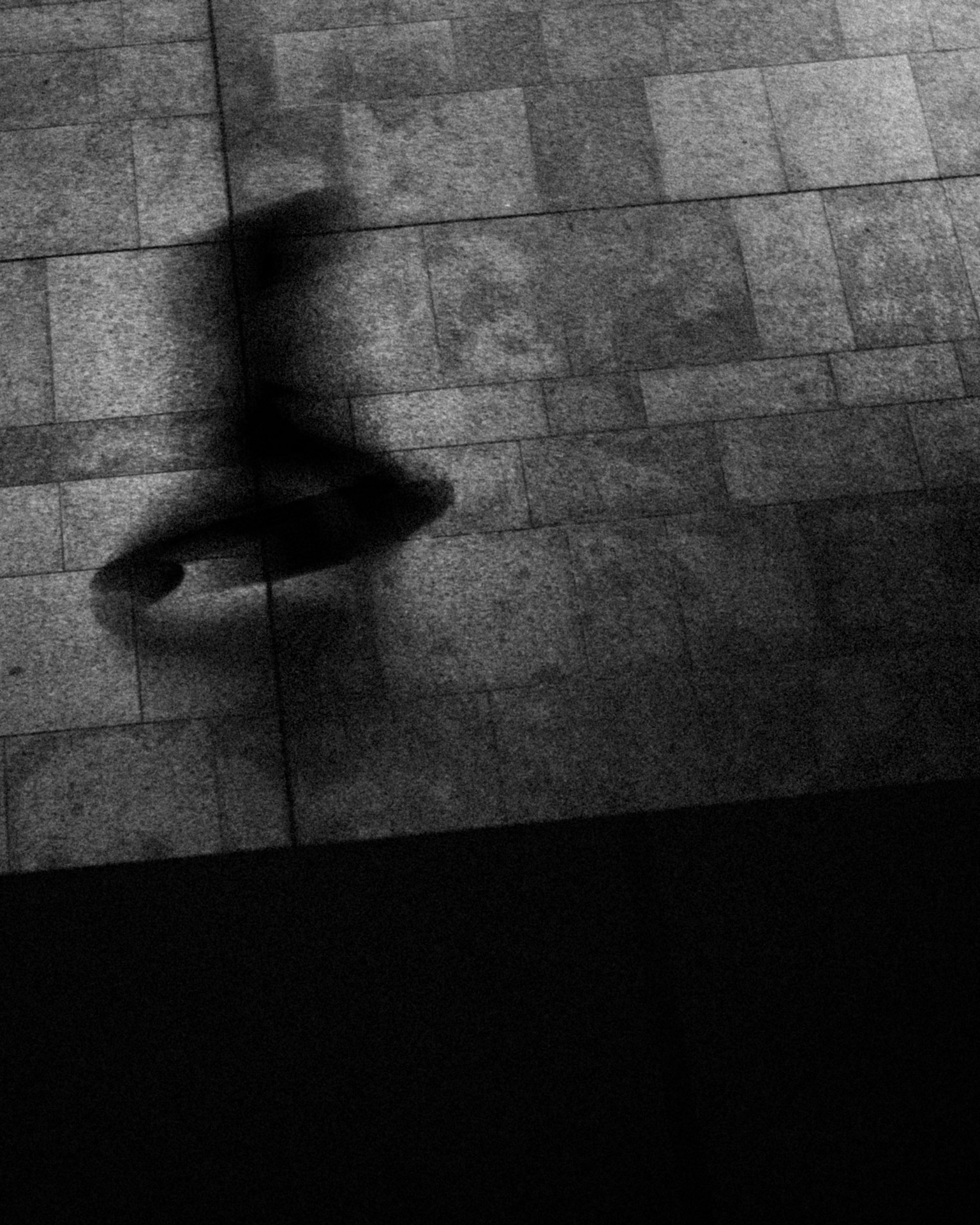 L'ombre d'une personne en mouvement marchant sur un sol en pierre en noir et blanc